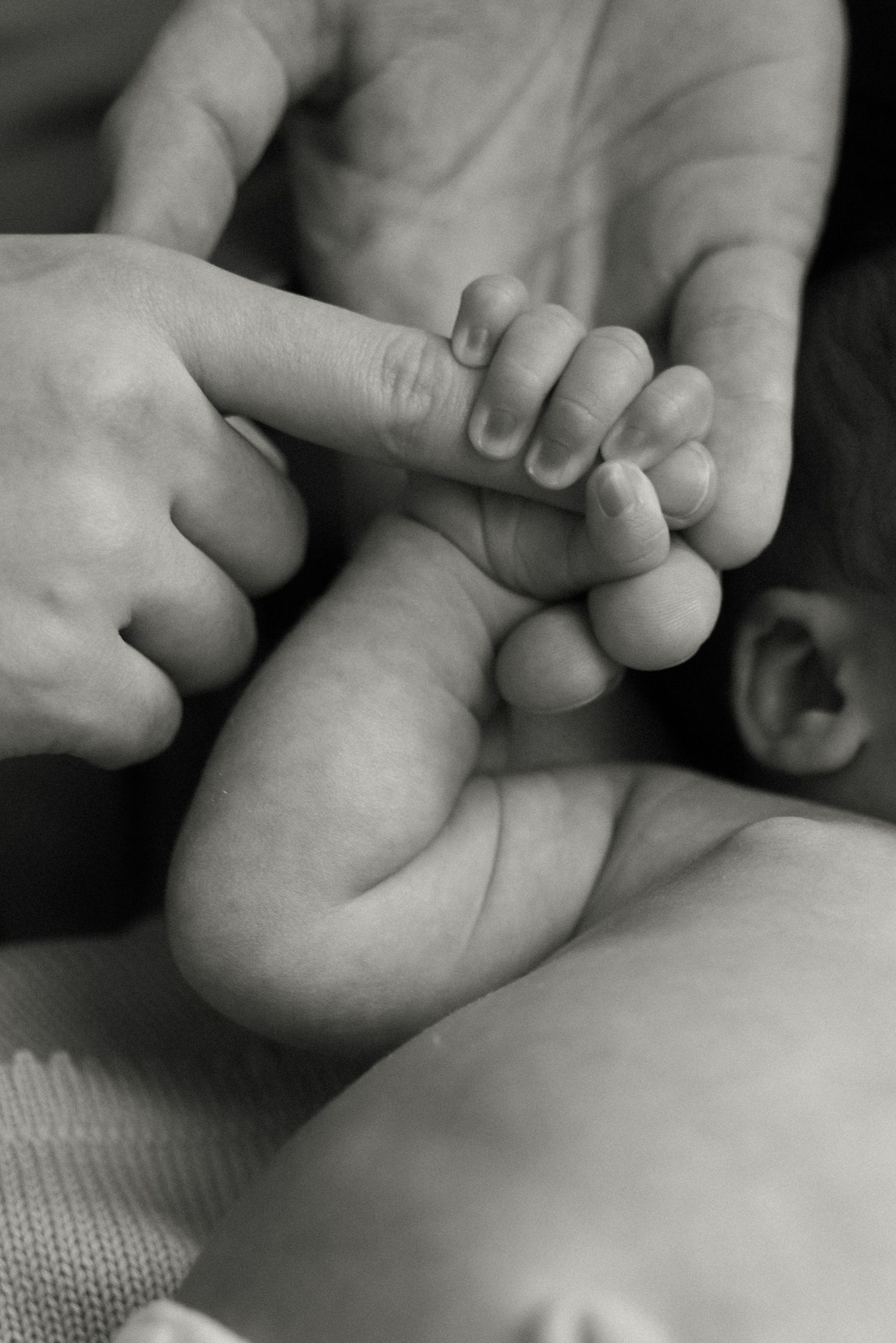 A series of black and white close-up photographs showing gentle massage techniques on a baby's foot.