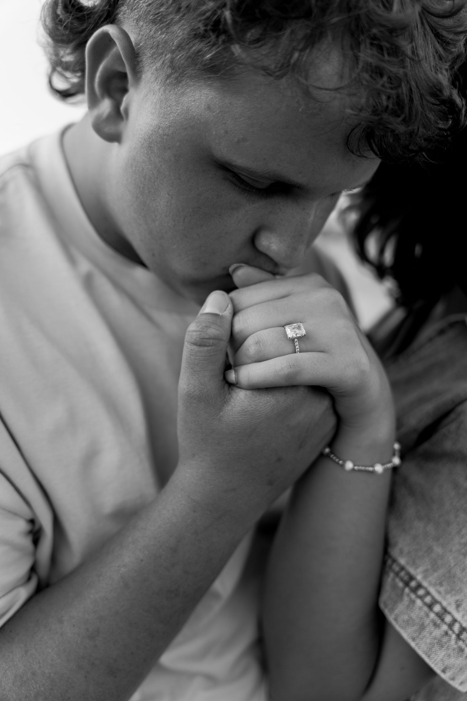 Black and white close-up of a groom kissing his bride's hand, highlighting her engagement ring. Oklahoma wedding photographer, Julie Lawson.