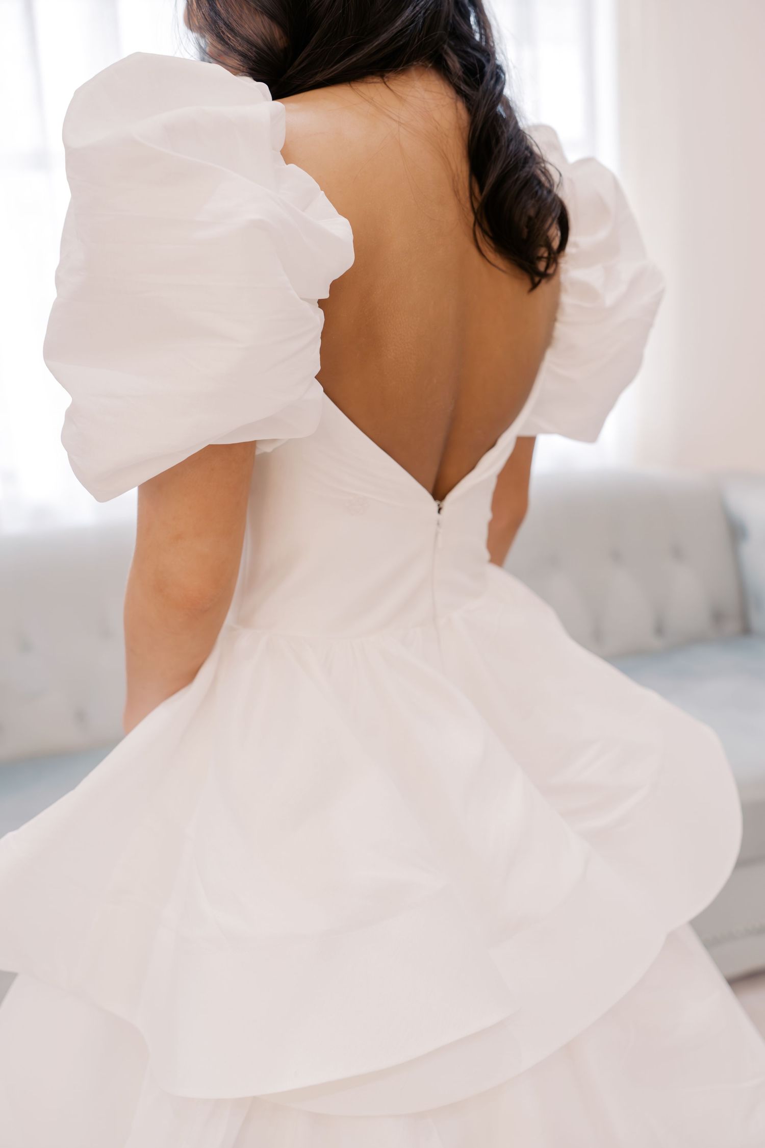 Bride wearing an elegant white wedding dress with ruffled puff sleeves and an open back at Sorelle at Meadow Creek wedding venue in Oklahoma