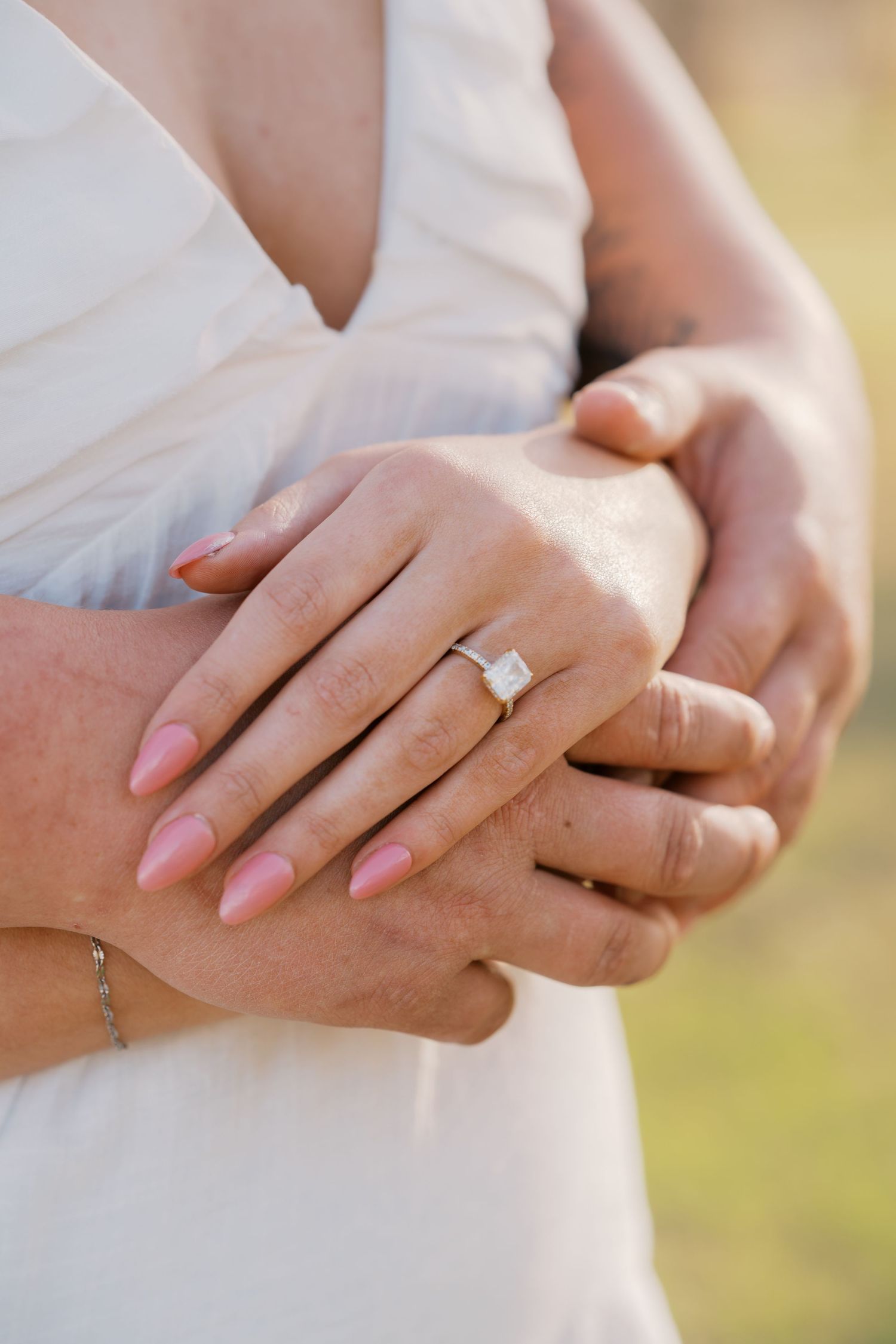 Close-up of engaged couple's hands showing a stunning emerald-cut diamond engagement ring.