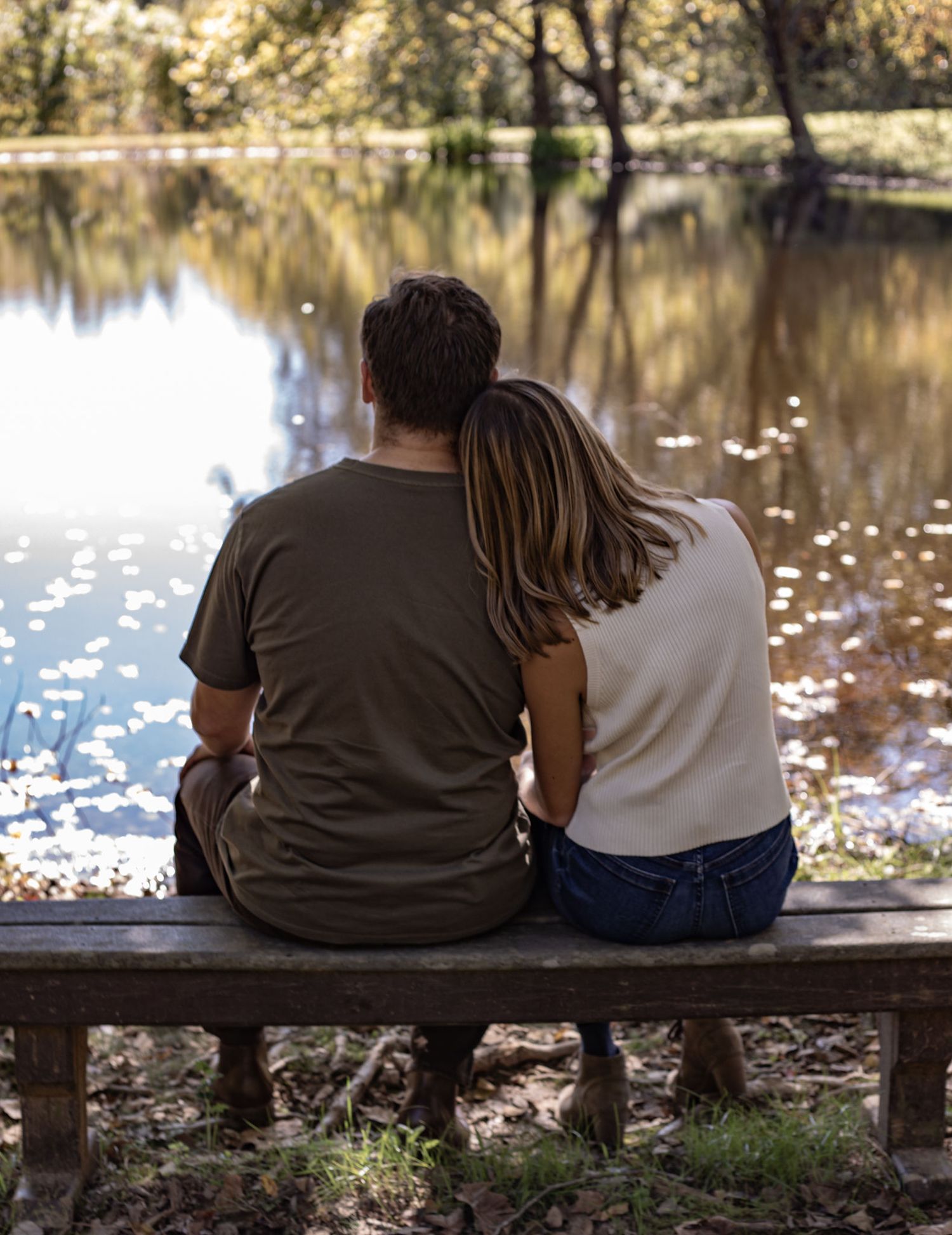A couple sitting together on a bench overlooking a peaceful pond.
