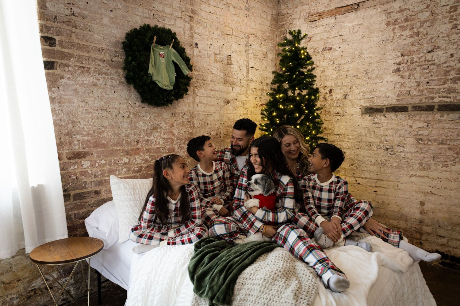 Family photo session with Christmas decorations and exposed brick wall background.