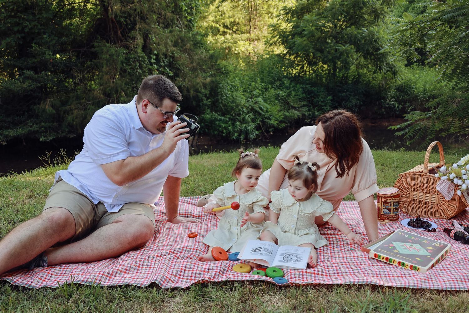 A family picnic scene with a red and white checkered blanket in a peaceful park setting.