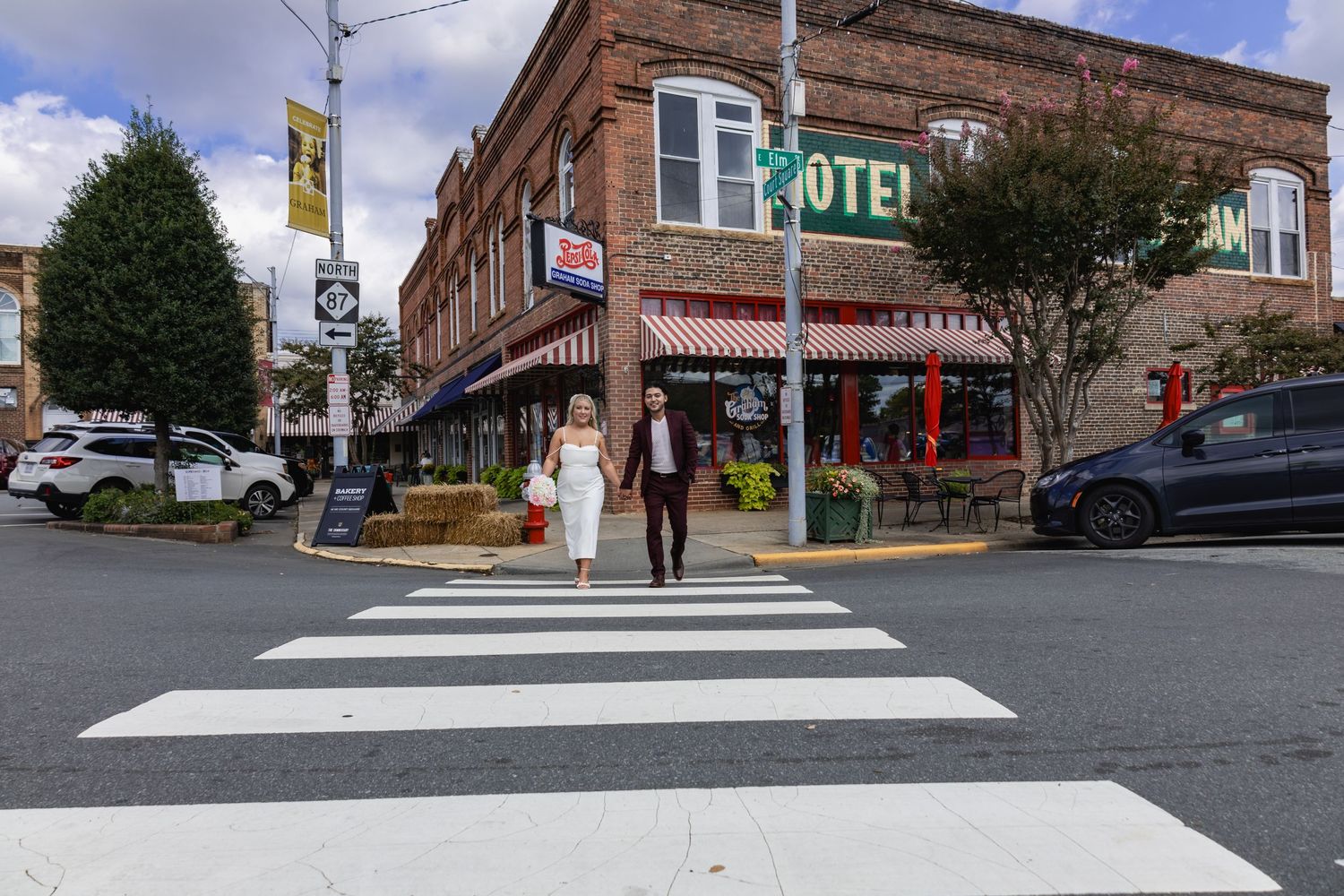 A street view of a historic brick hotel building with a crosswalk in the foreground.