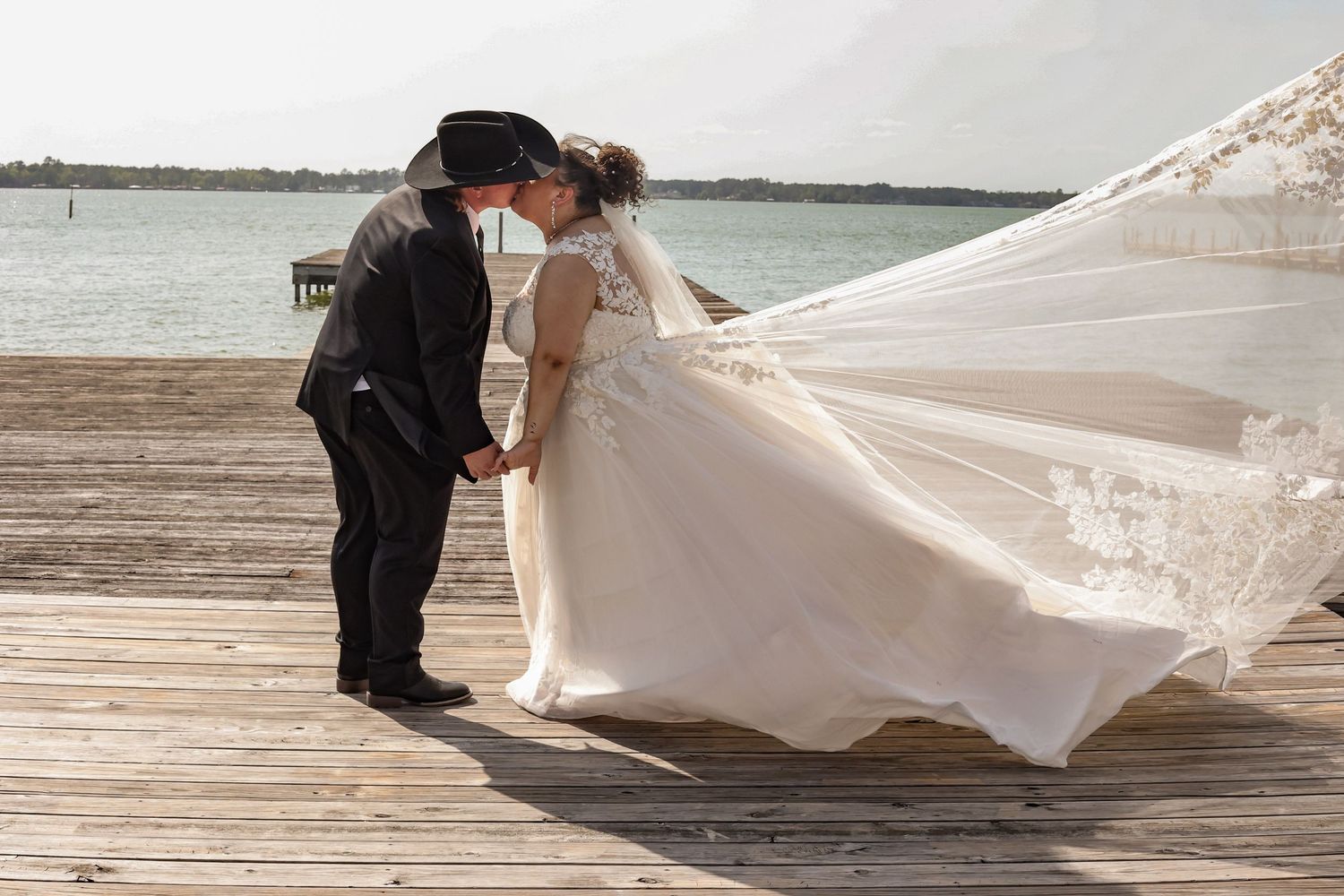 White wedding dress train flowing beautifully across a wooden dock by the waterfront.