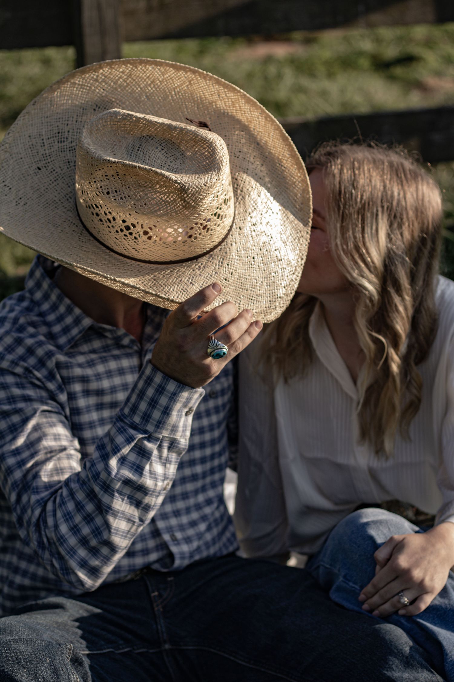 An intimate moment shared between a couple, one wearing a weathered cowboy hat.