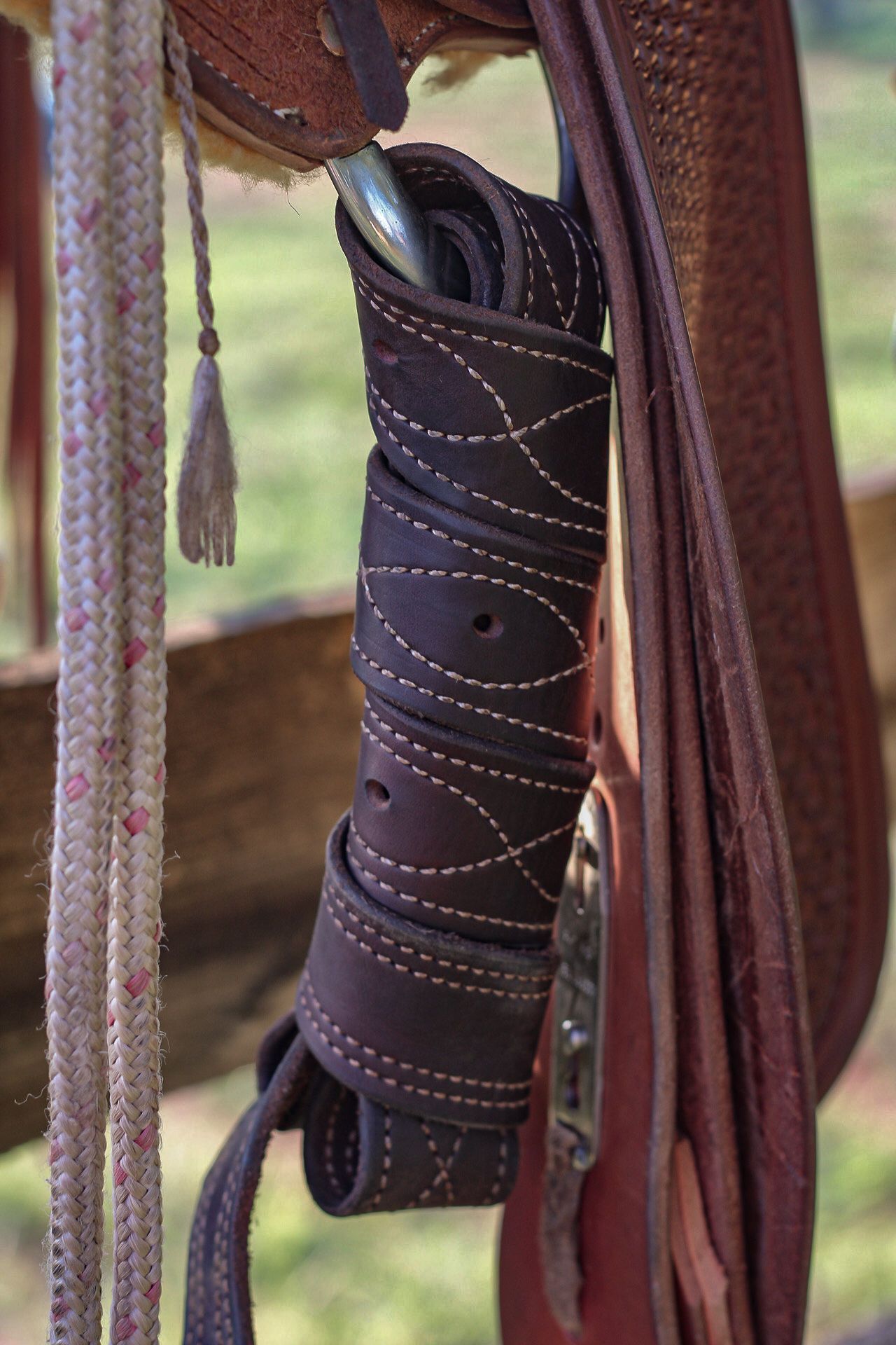 Close-up detail of ornate leather stitching on a brown western saddle or tack.
