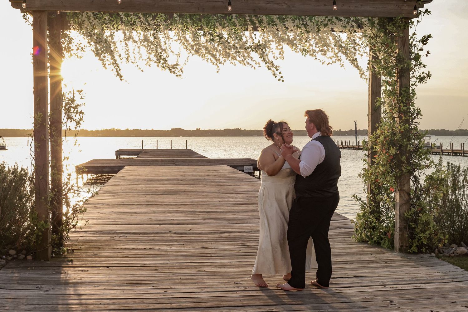 Scenic wedding ceremony setup on waterfront dock at golden hour.