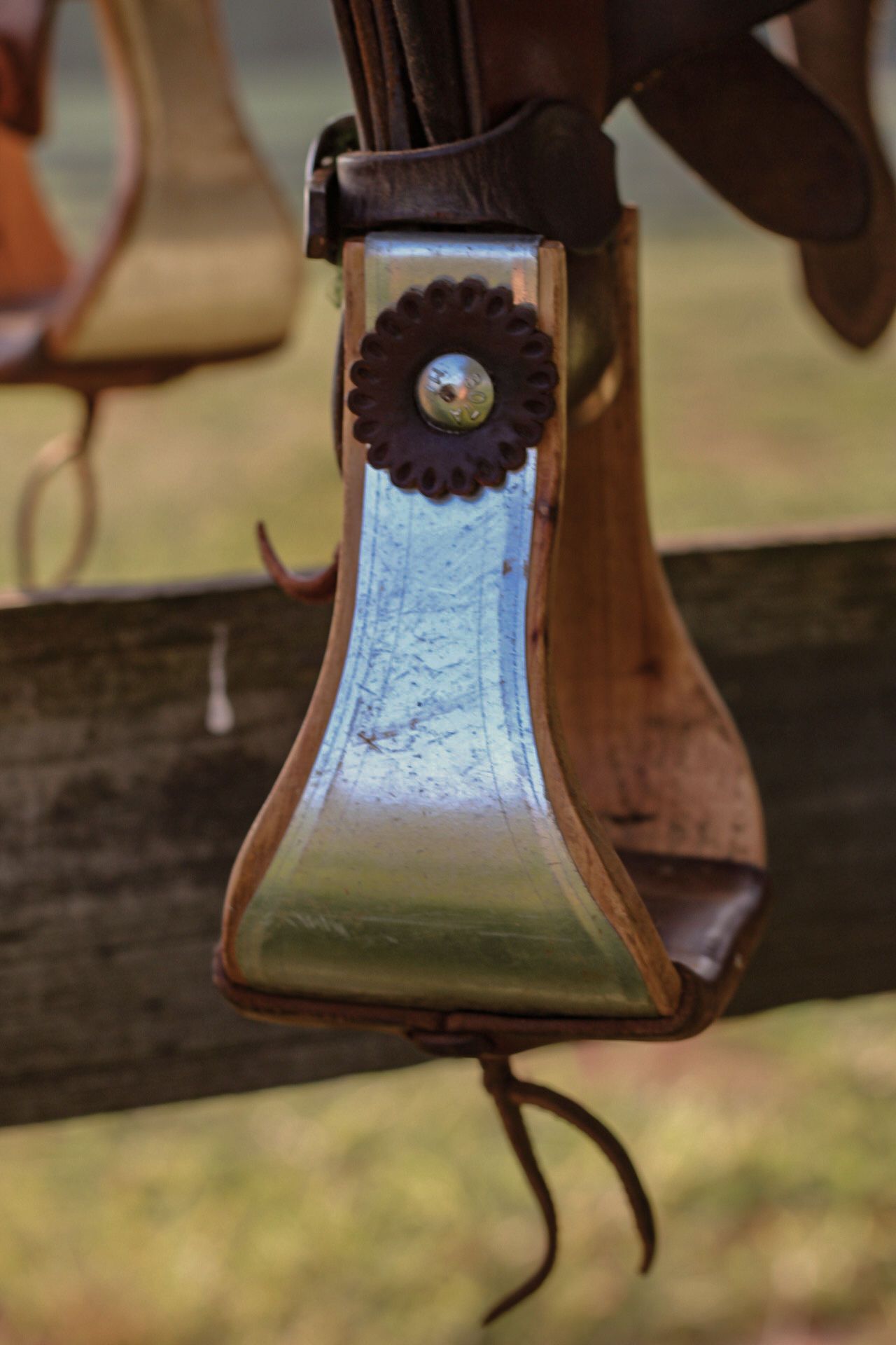 Detailed view of a blue and silver stirrup on leather horse tack.