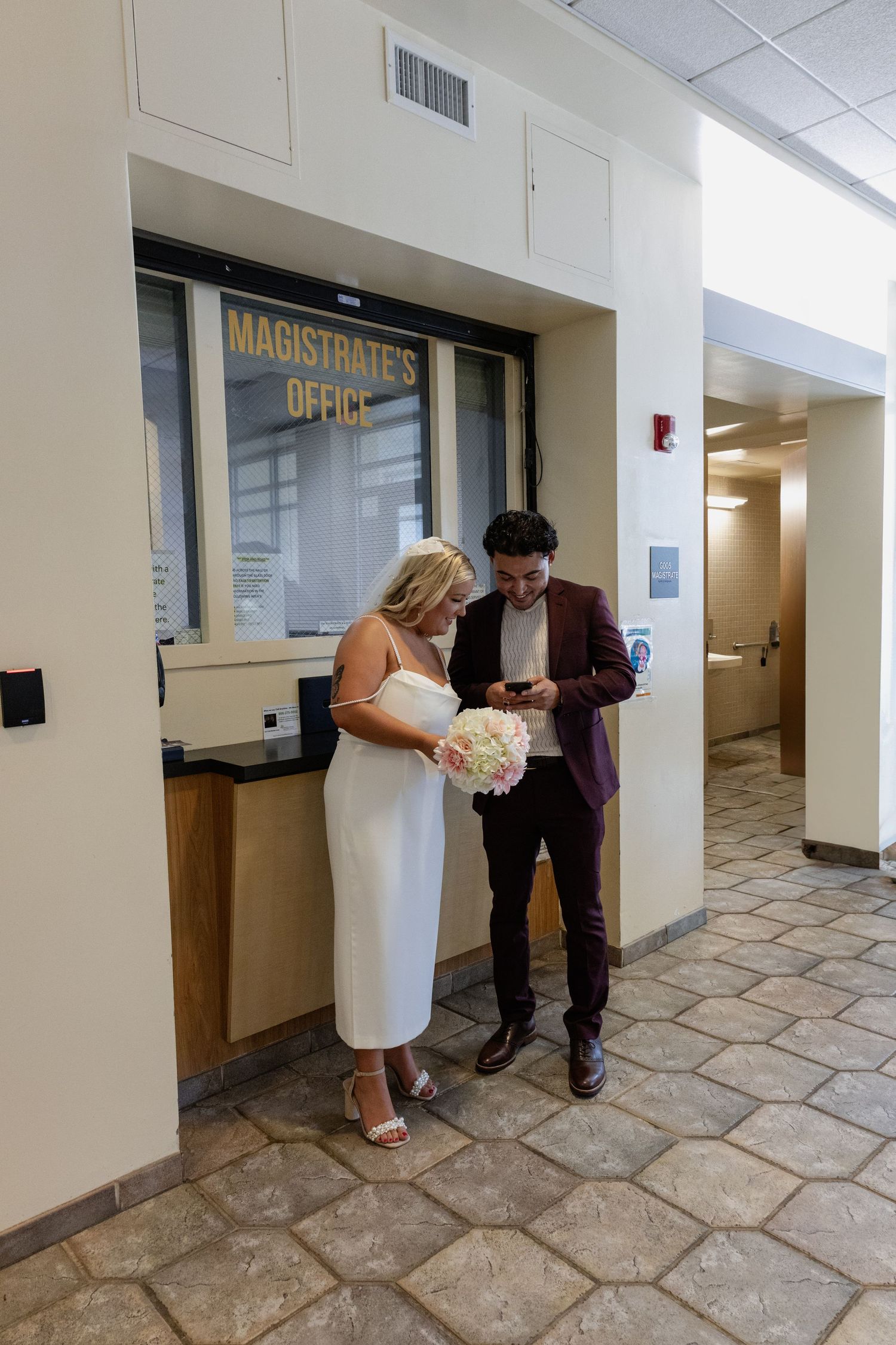 A couple checks their phone outside a magistrate's office.