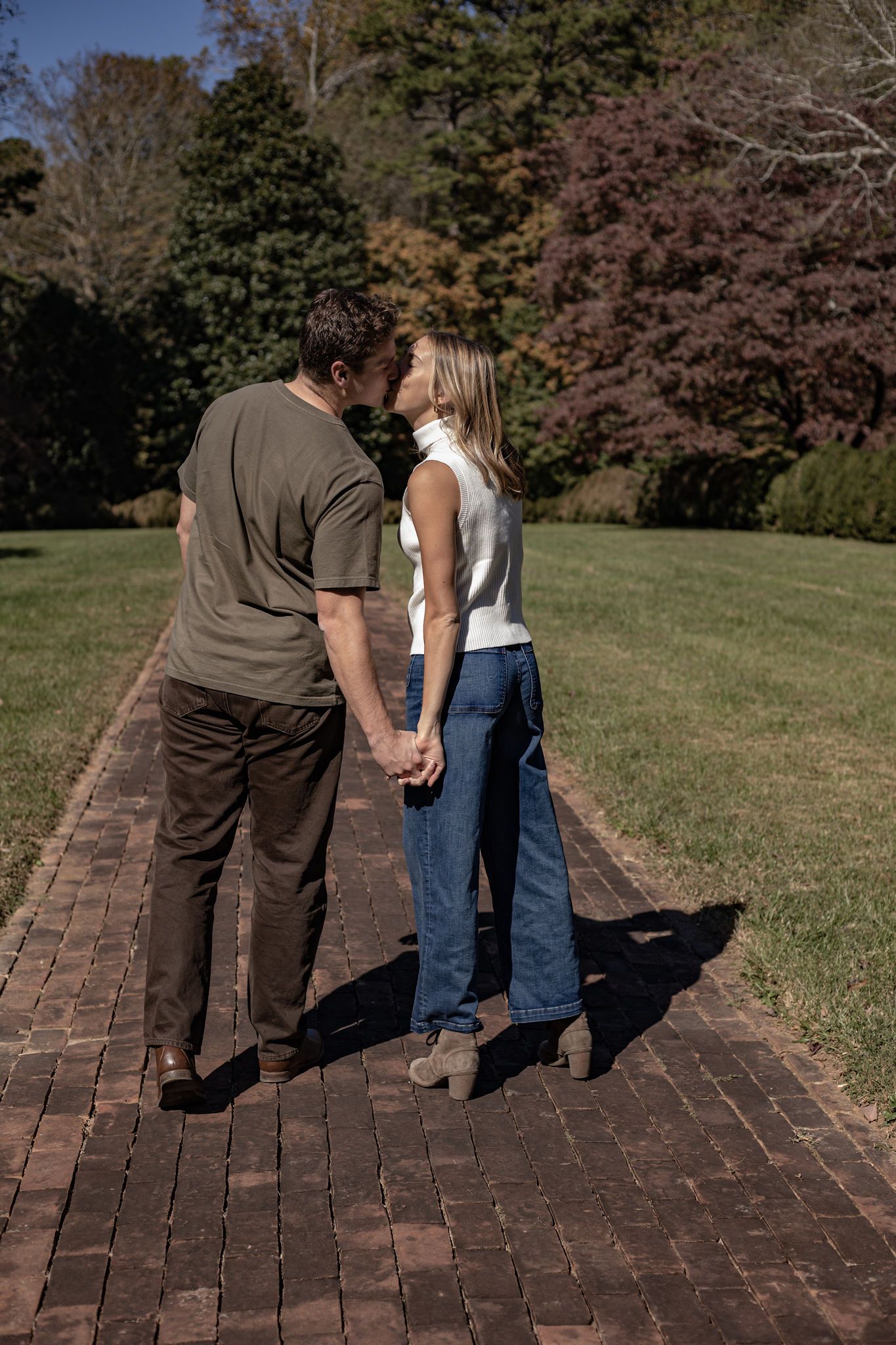 A couple sharing an intimate moment on a brick pathway in autumn.