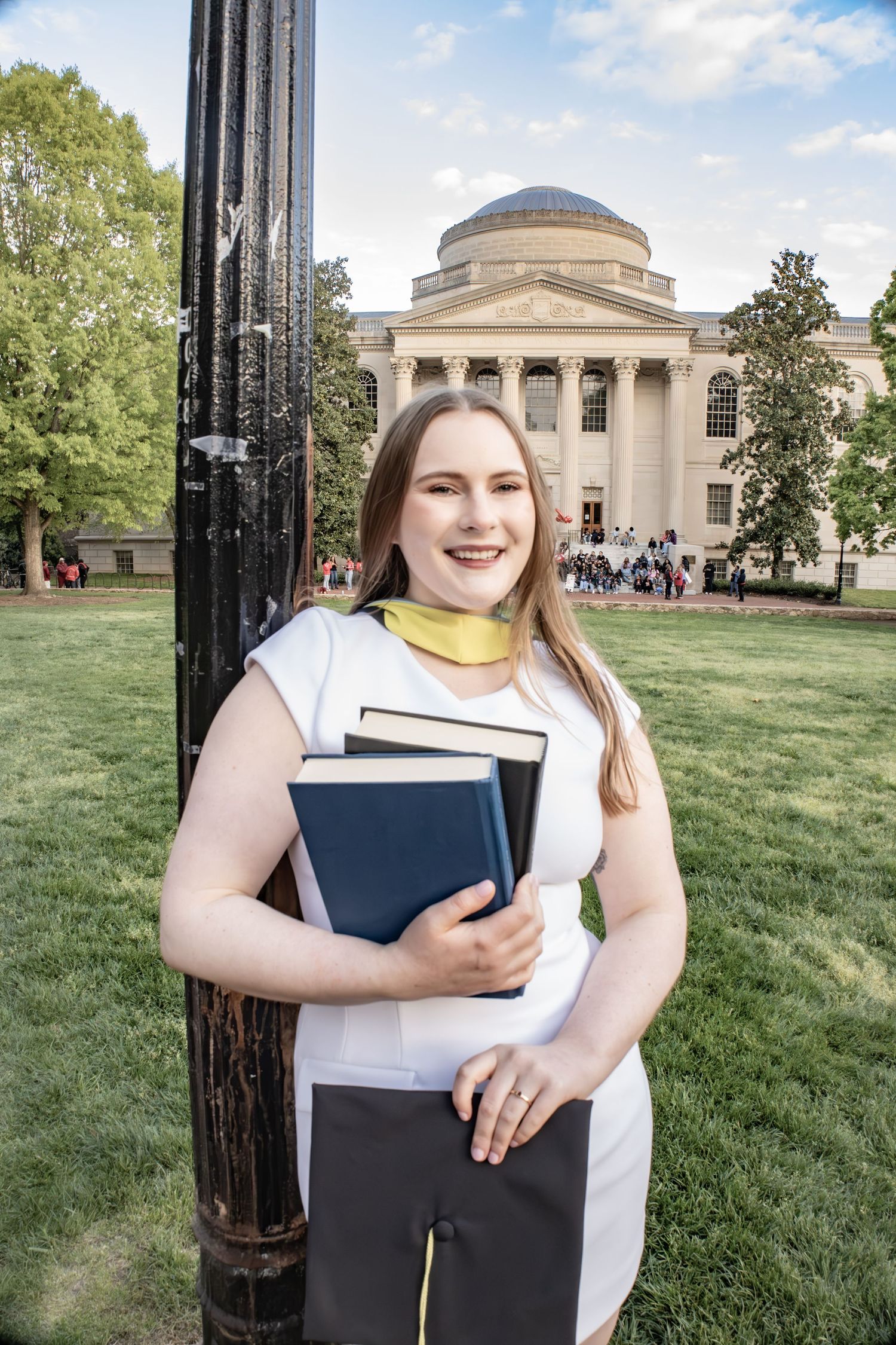 Student holding books poses in front of classical university building.