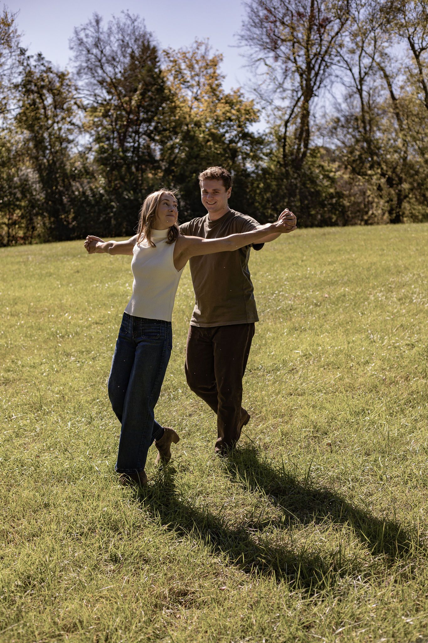 A couple dancing together in a sunny field.