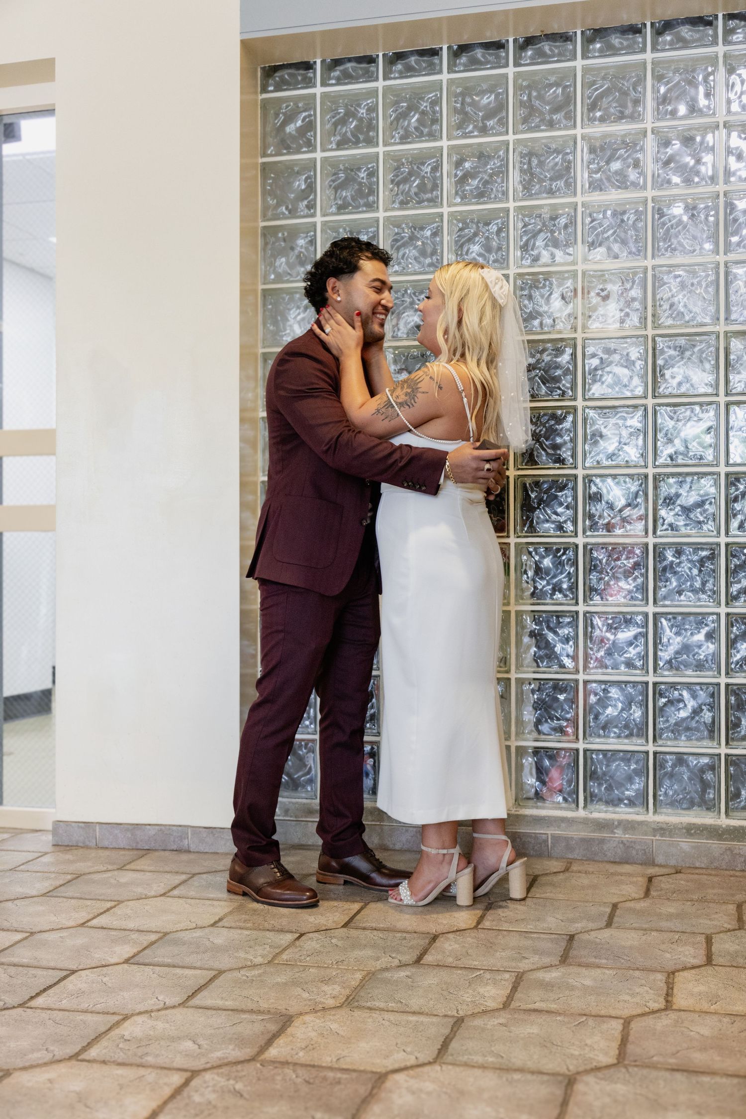 A couple sharing a joyful laugh while standing against a decorative glass wall.