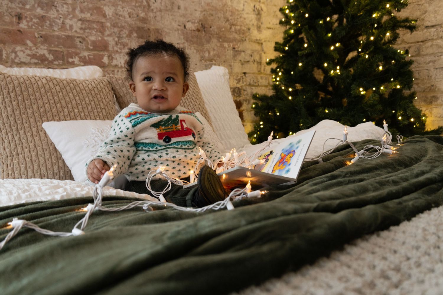 Candid holiday photos on cozy blankets with Christmas tree lights twinkling in background.