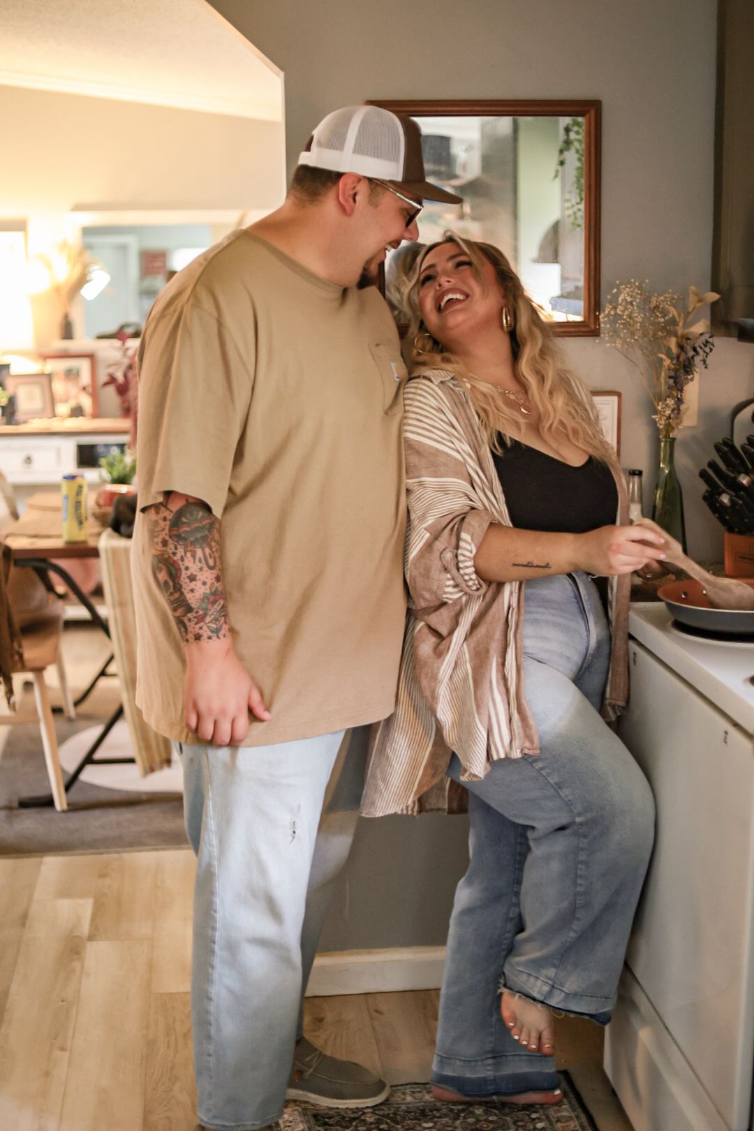 A couple shares a joyful moment together while cooking in their kitchen.