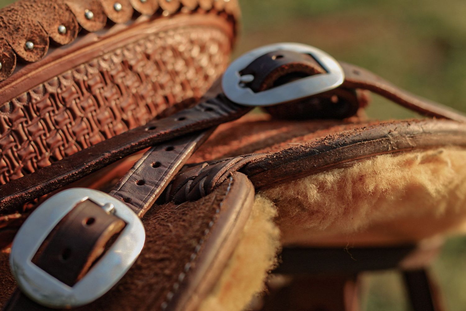 Close-up of silver buckles and leather straps on a western saddle with sheepskin lining.