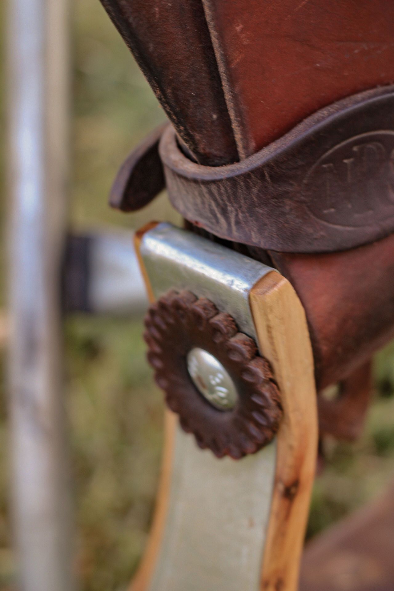 Detail shot of a metal concho fastener on brown leather western saddle.