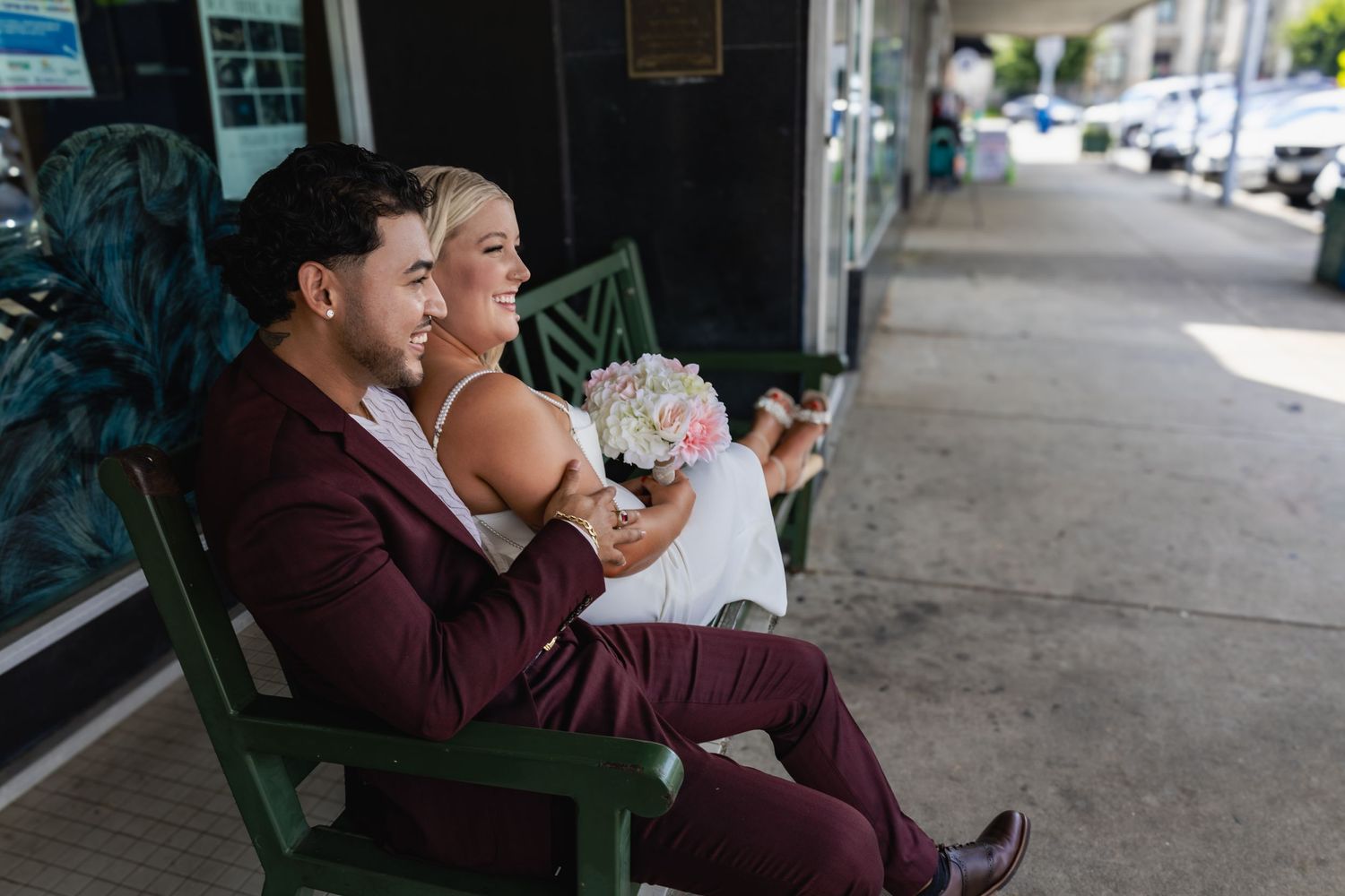A couple sits on a green bench sharing a tender moment.