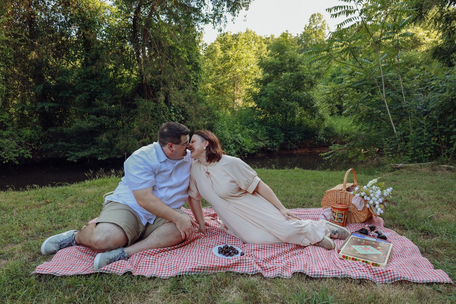 A romantic picnic setup with a classic red checkered blanket in a serene park setting.