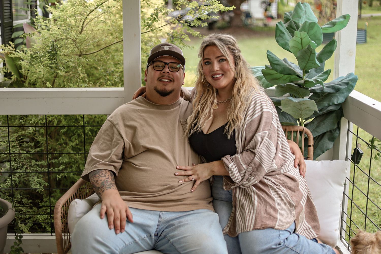 A couple sitting together on their porch surrounded by plants.