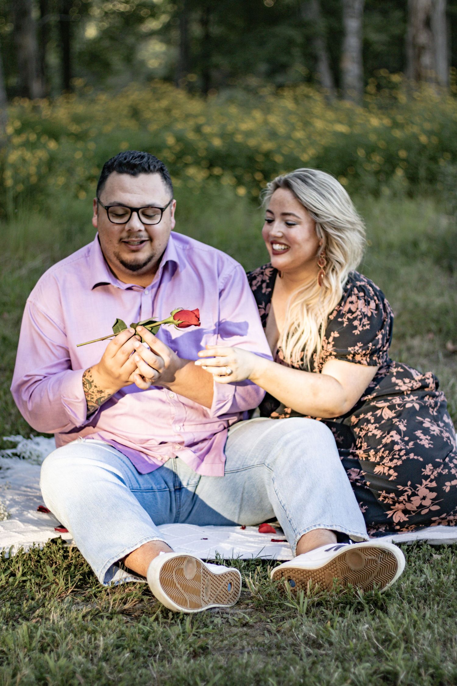 A couple laughs together while enjoying snacks during their outdoor picnic date.