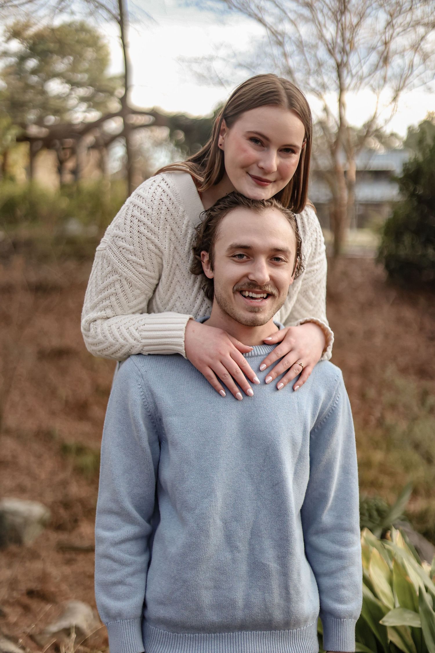 Couple in casual sweaters poses together outdoors during autumn.