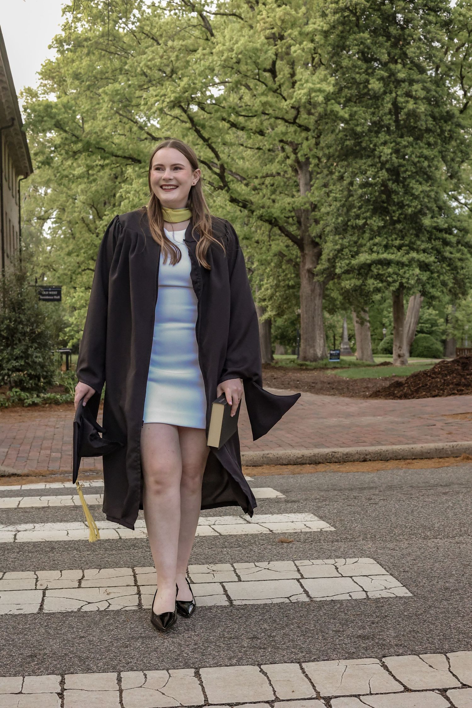 Fun graduation portrait session on a brick pathway surrounded by trees.