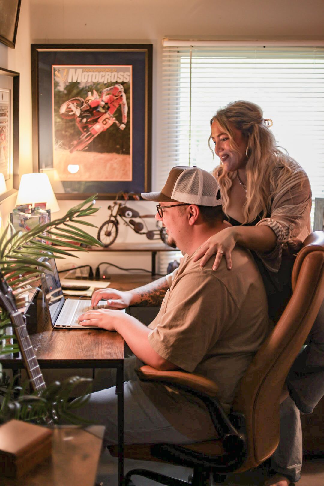 A couple spending time together at a home office desk.