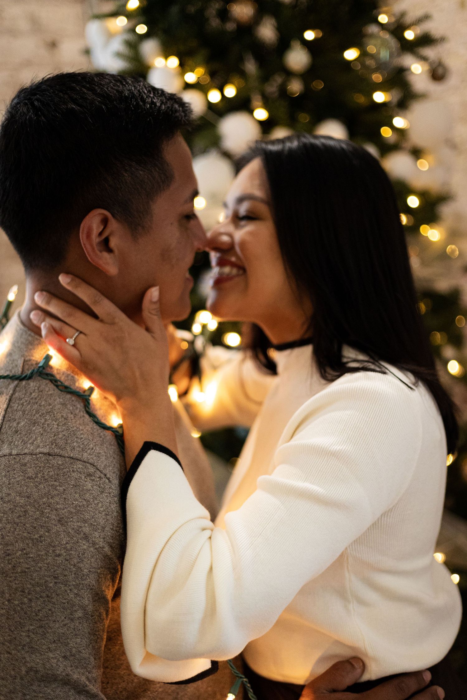 An intimate moment between a couple with Christmas lights glowing in the background.
