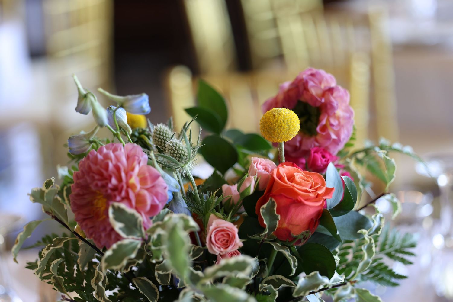 A delicate floral arrangement with pink carnations, coral roses and green foliage in soft focus.
