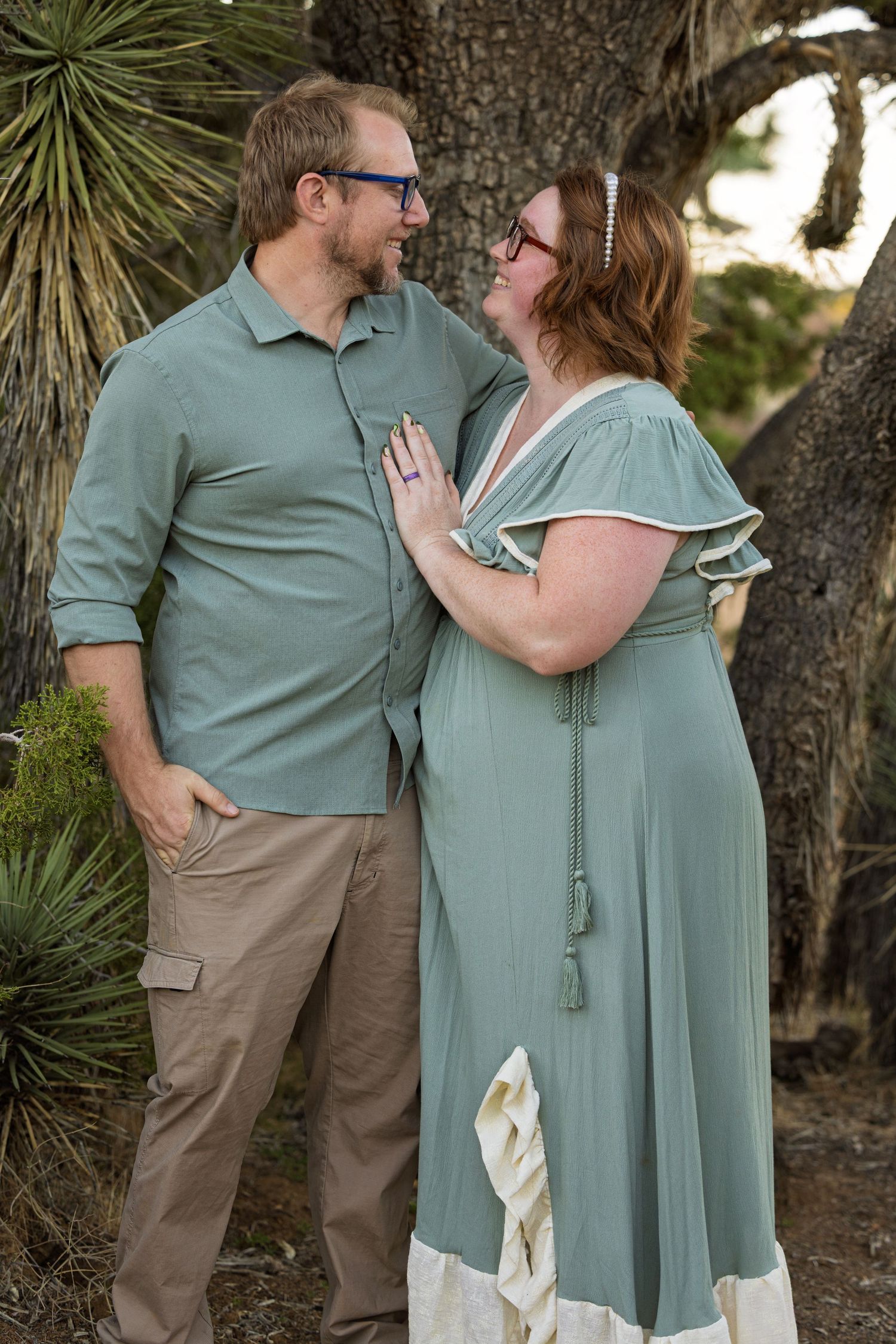 A couple in coordinating sage green outfits share romantic moments together in a natural outdoor setting.