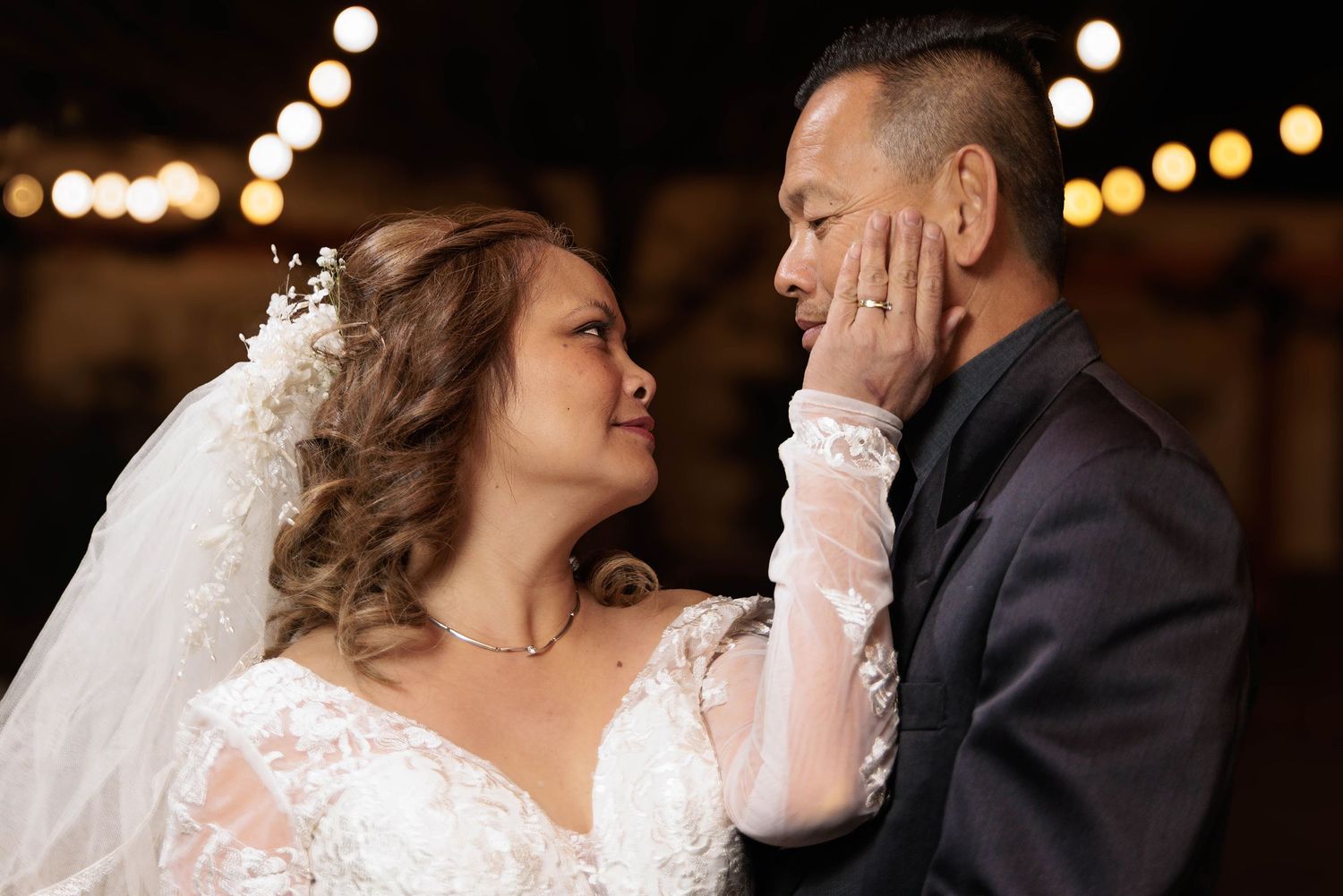 Romantic wedding moment captured as couple shares emotional embrace under glowing lights.