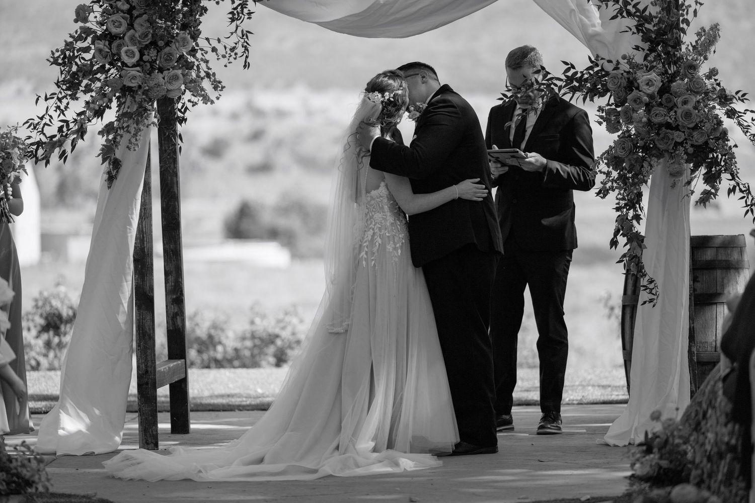 A romantic black and white wedding ceremony moment under a floral arch.