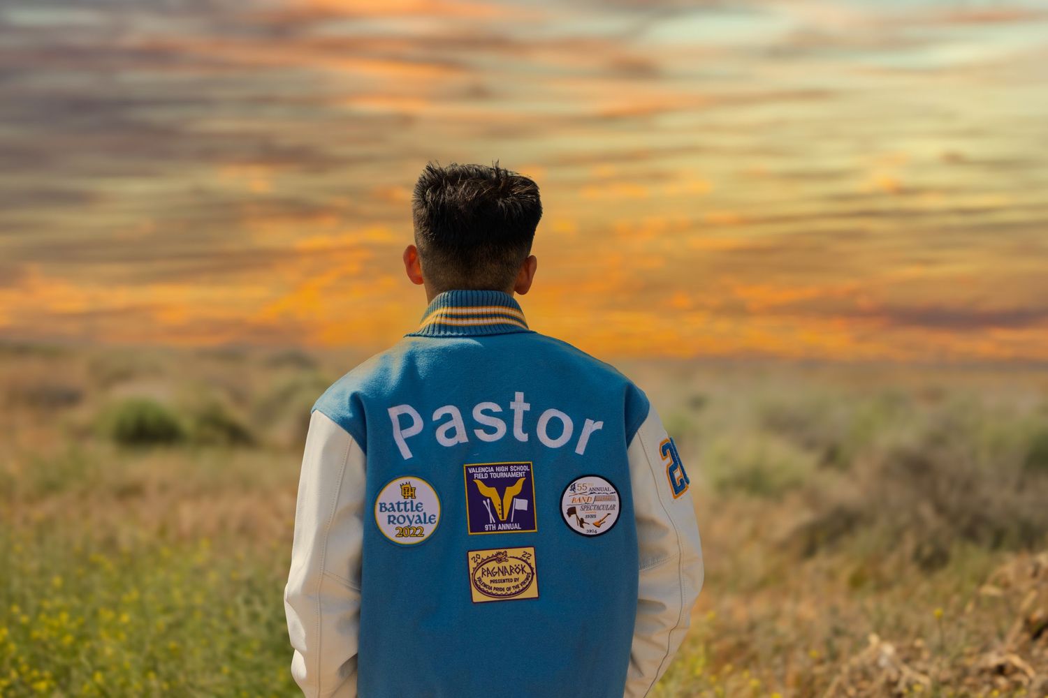 A figure wearing a varsity jacket with 'Pastor' text stands in a field against a vibrant orange sunset sky.