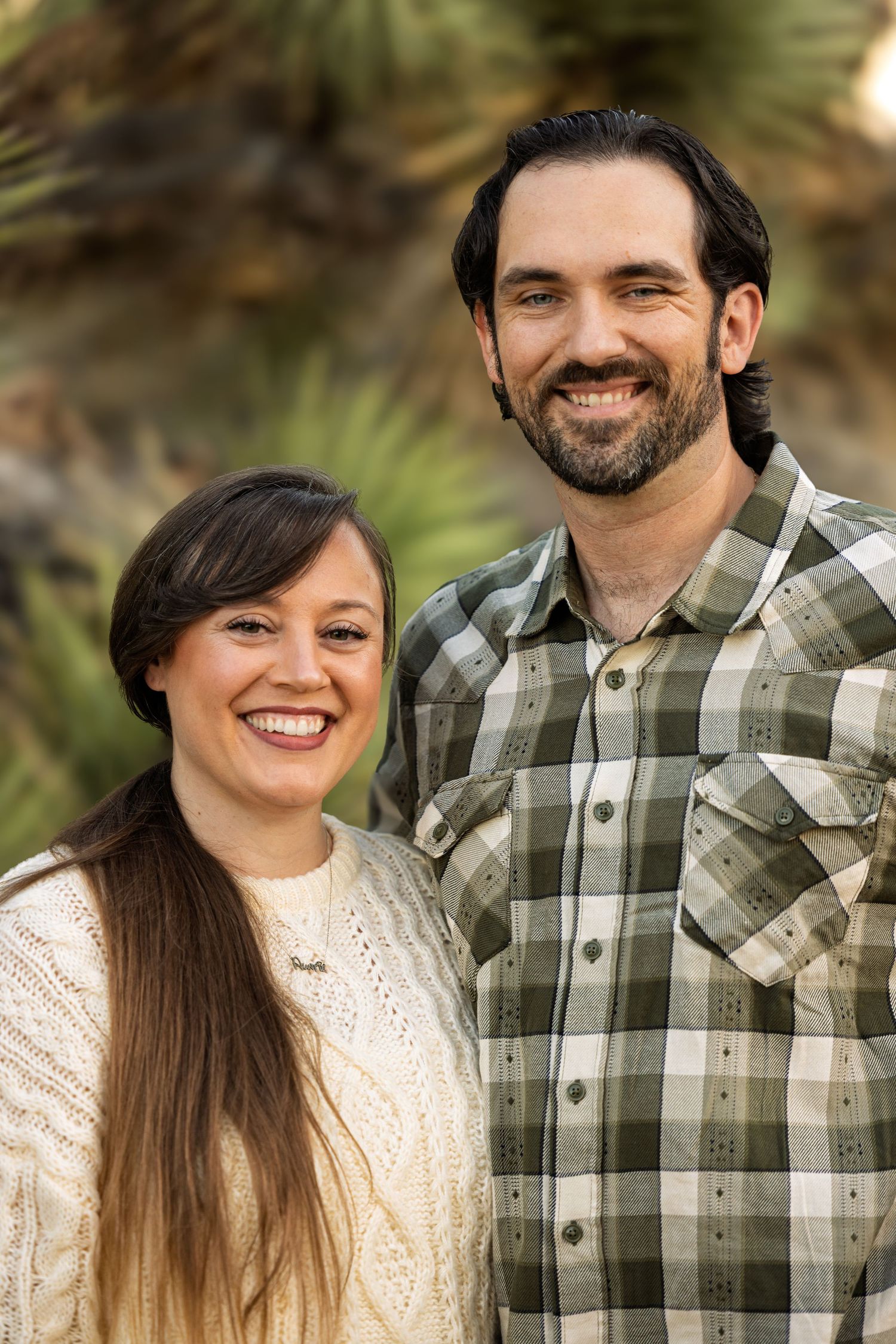 A couple in casual outdoor wear share candid moments together in a natural setting.