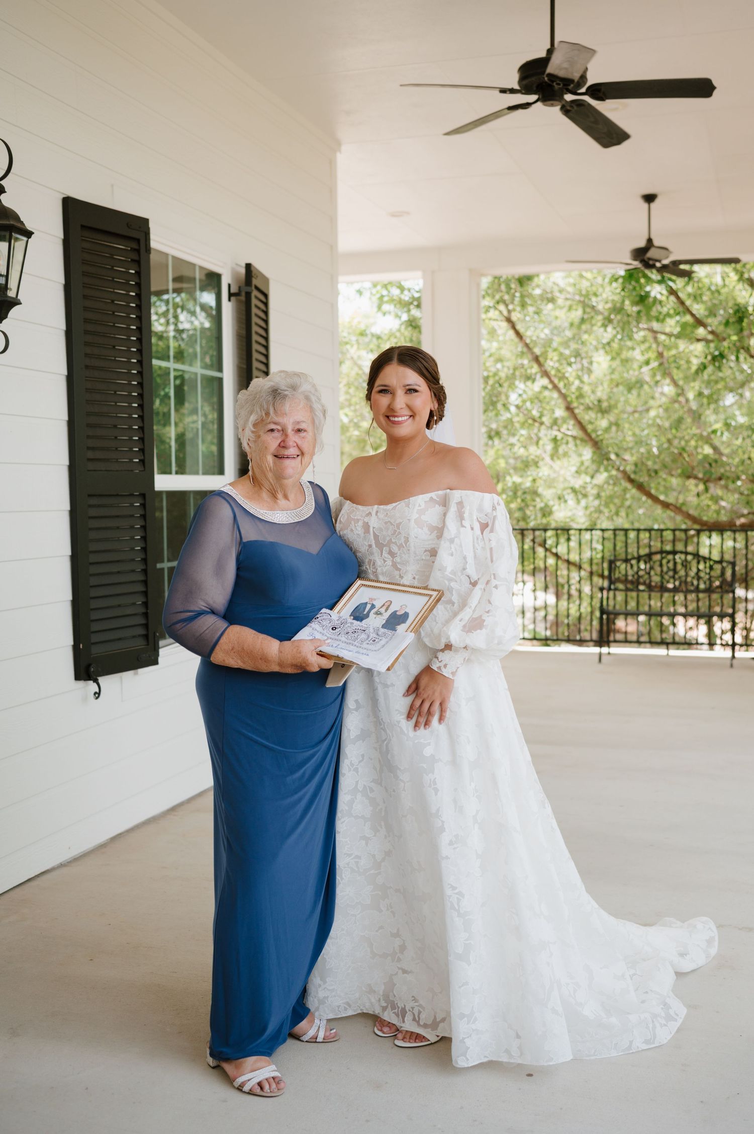 A touching moment between family members as they admire a beautiful white wedding dress on an elegant covered porch.