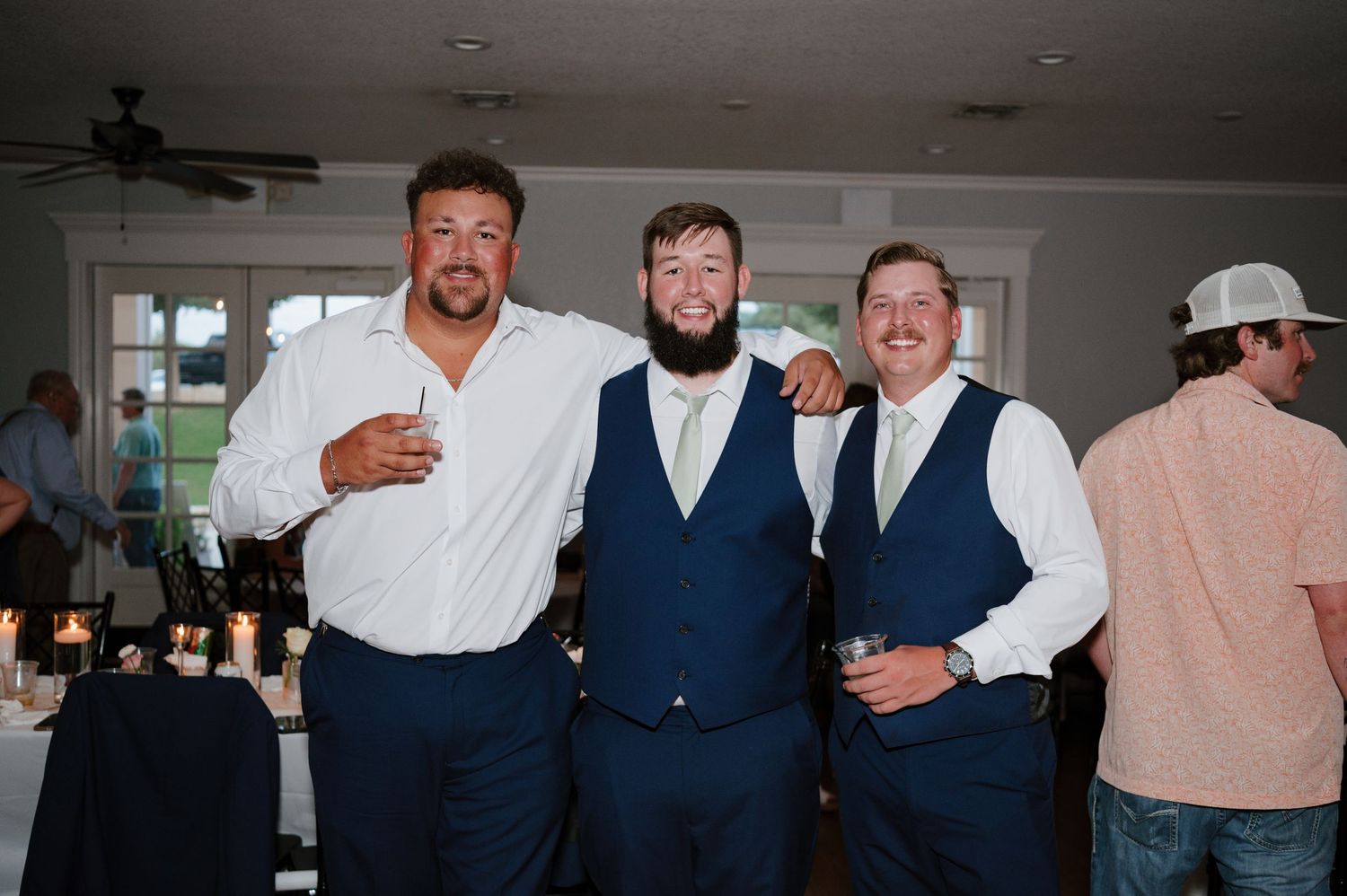Wedding party members in navy blue suits and white shirts celebrating indoors.