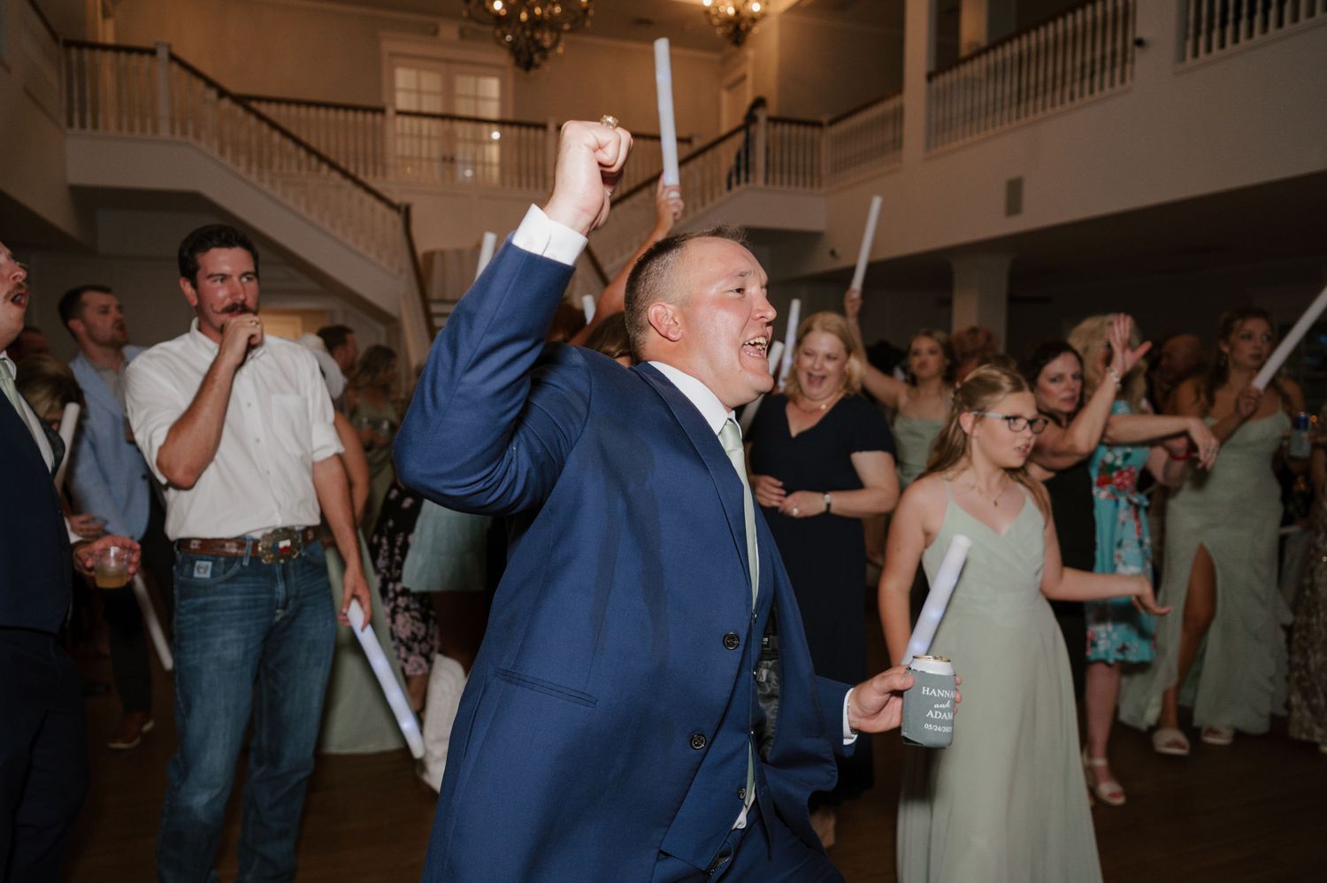 Wedding guests dancing and celebrating in an elegant venue with white columns and balconies.
