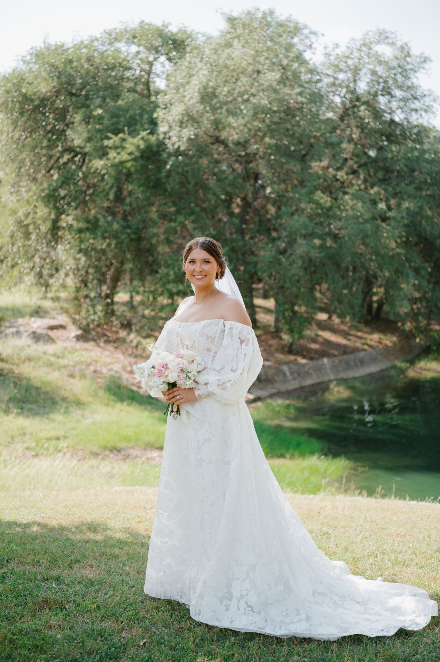 White wedding dress with lace details photographed outdoors against natural greenery.