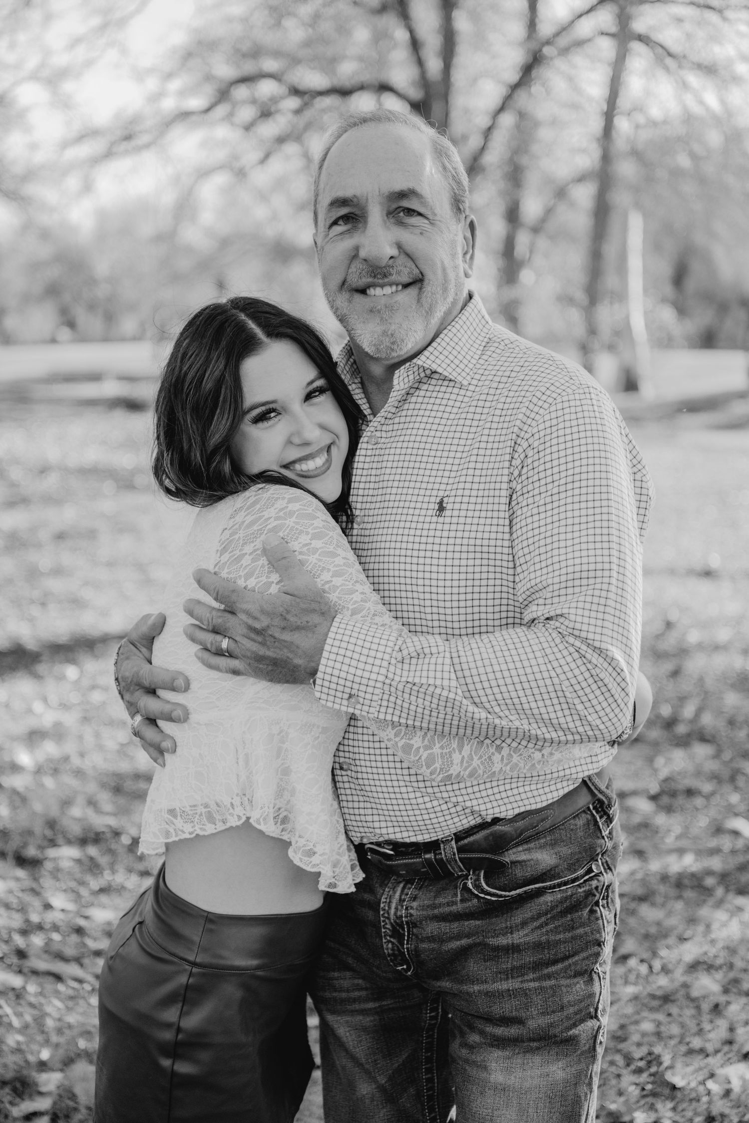Black and white outdoor portrait series showing a sweet embrace between two people in a natural setting with fallen leaves.