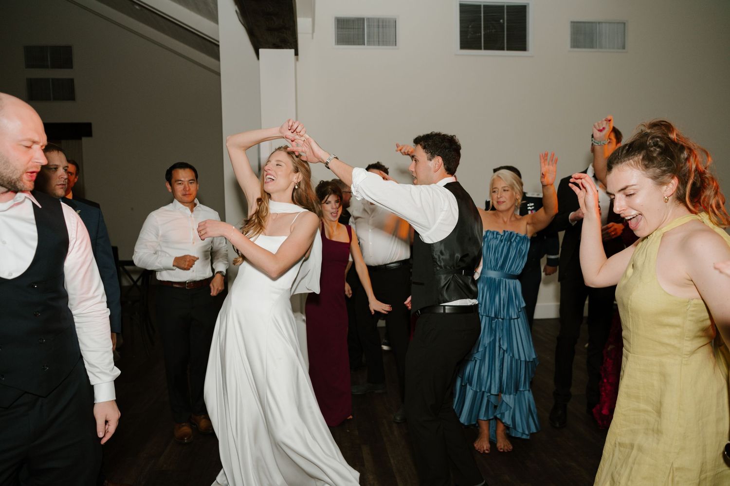 Wedding reception dance floor filled with celebrating guests in evening venue.