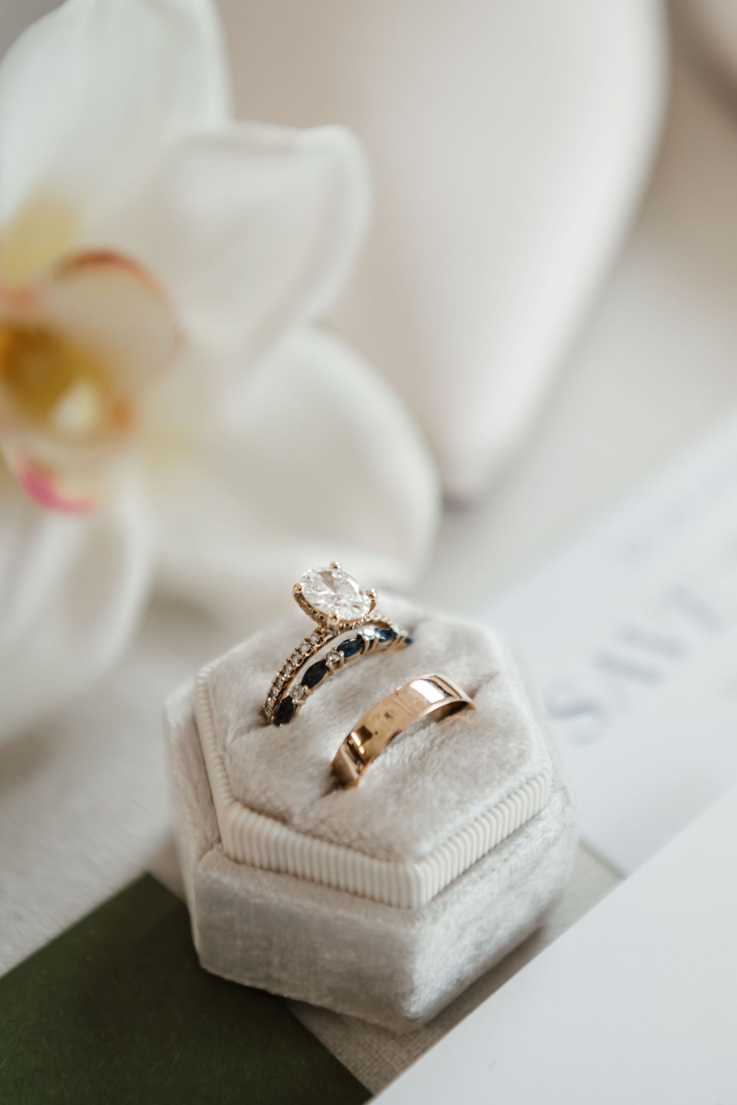 Wedding rings displayed on elegant cream-colored velvet ring boxes in a minimalist style.