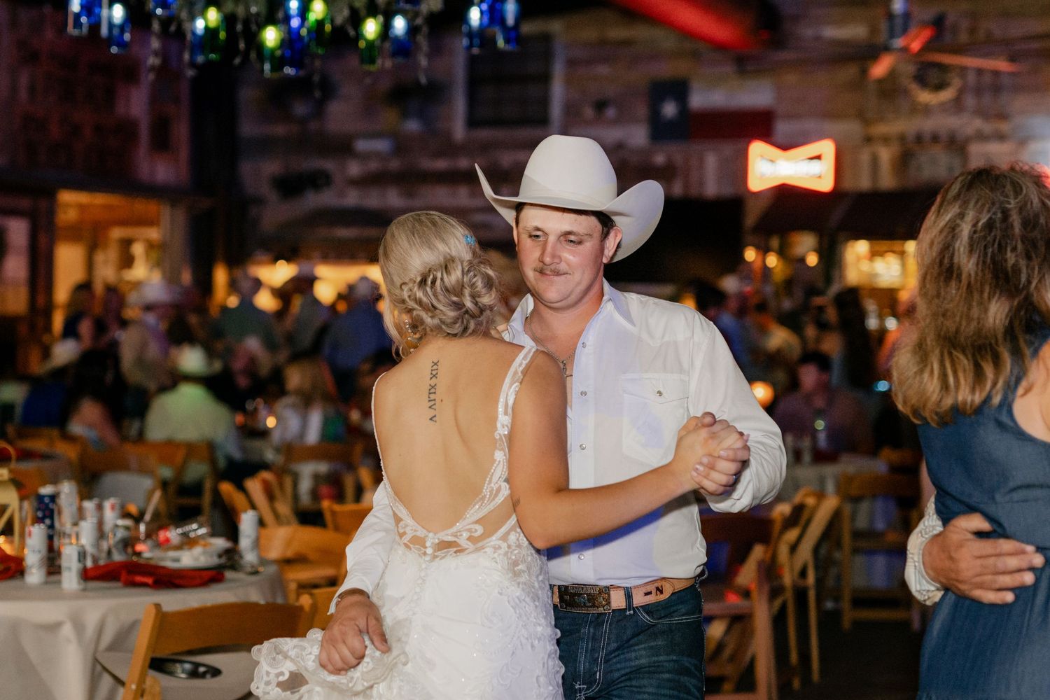 Couple slow dances at rustic barn wedding reception under string lights.