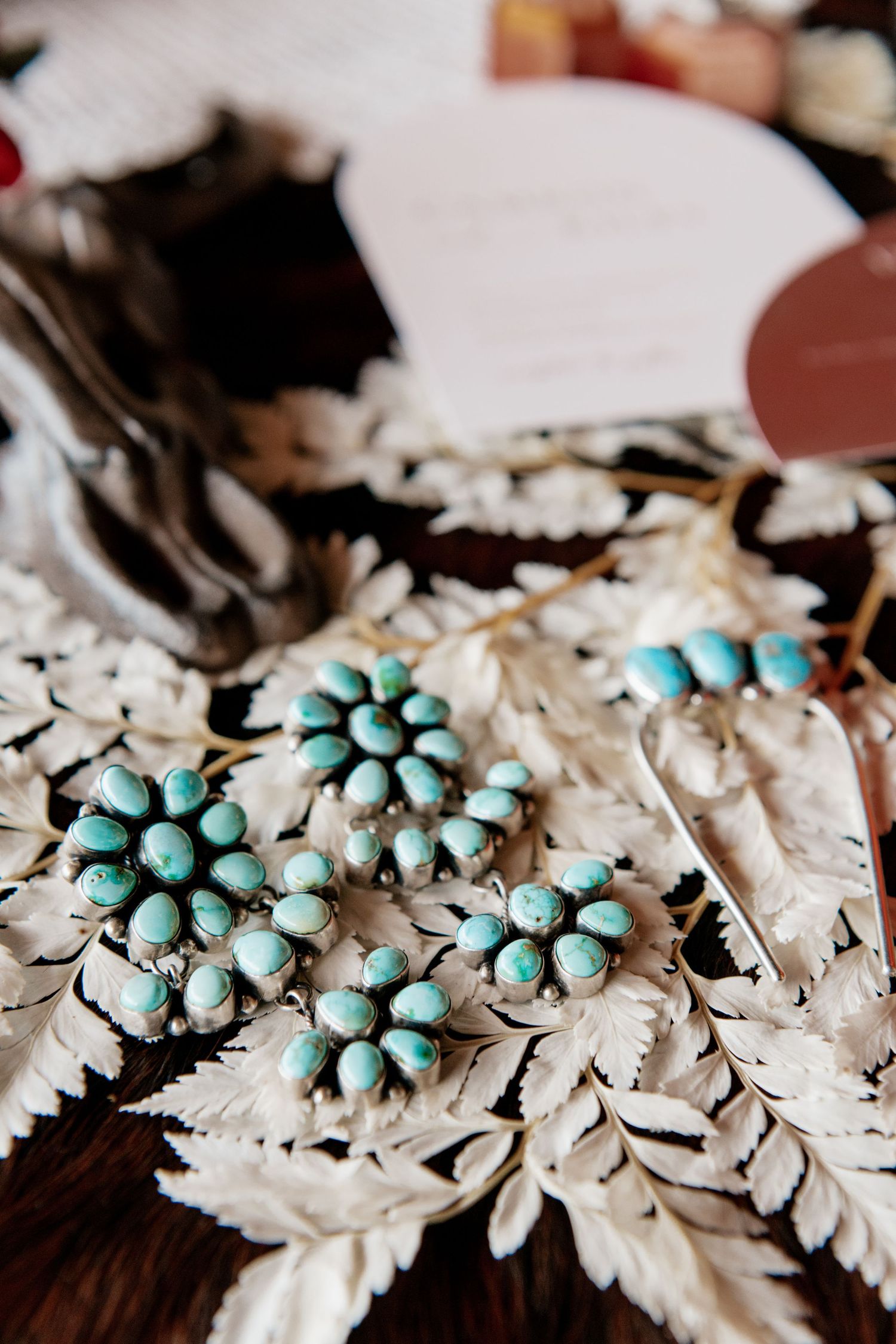 Turquoise flower-shaped jewelry pieces arranged on white lace with vintage styling.