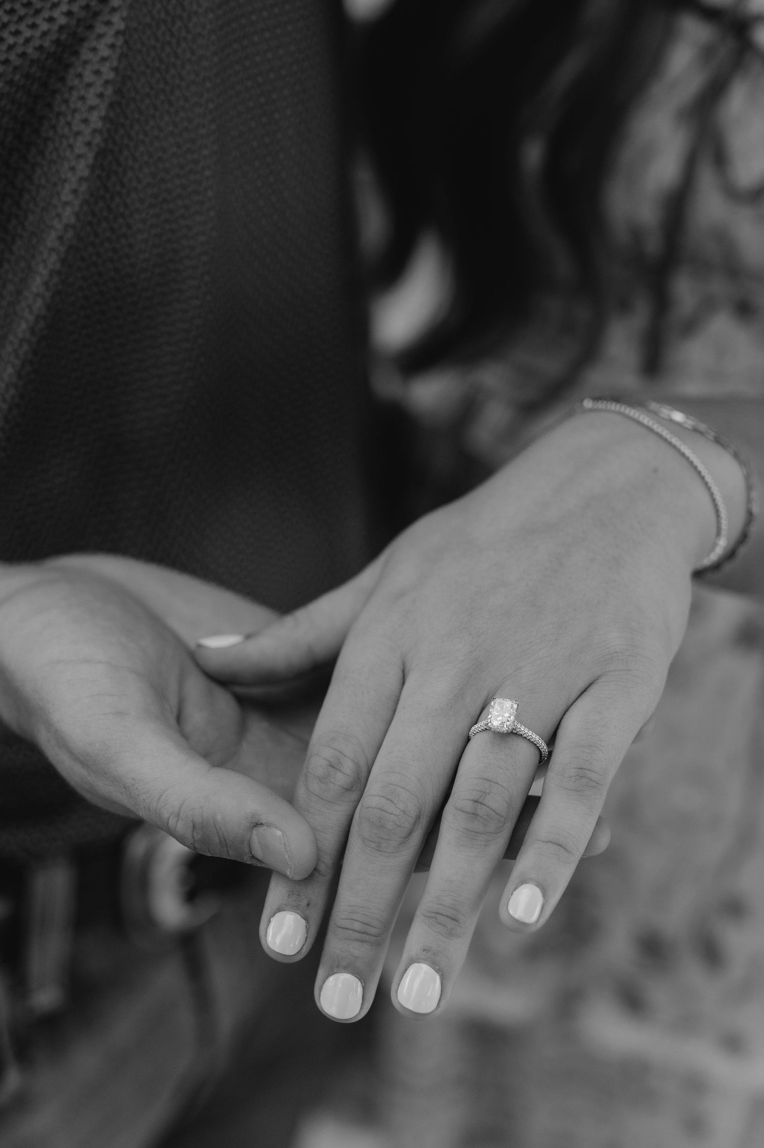 A black and white sequence of hands showing an engagement ring from different angles and perspectives.