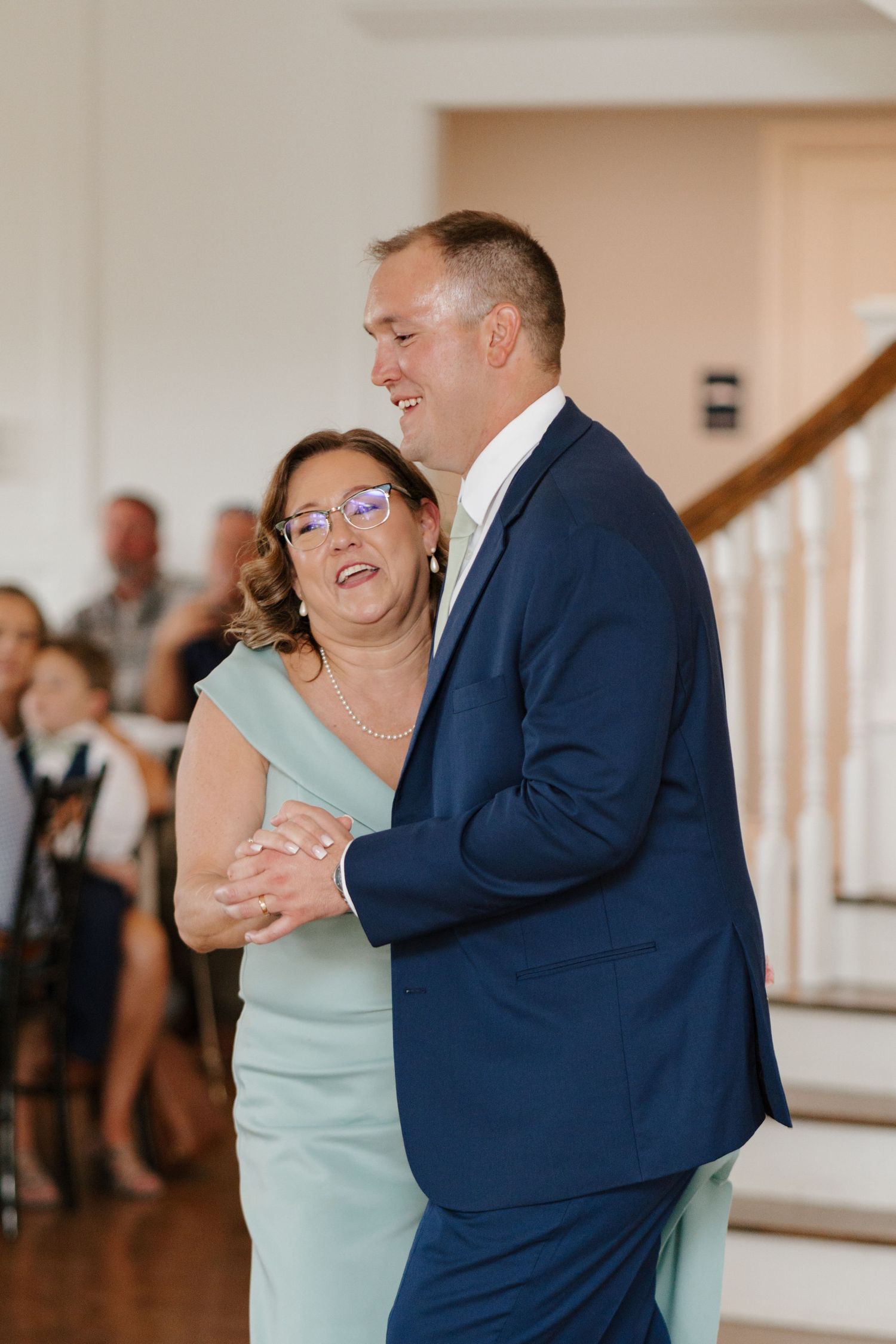 Wedding guests dancing together in formal attire at an indoor reception venue.