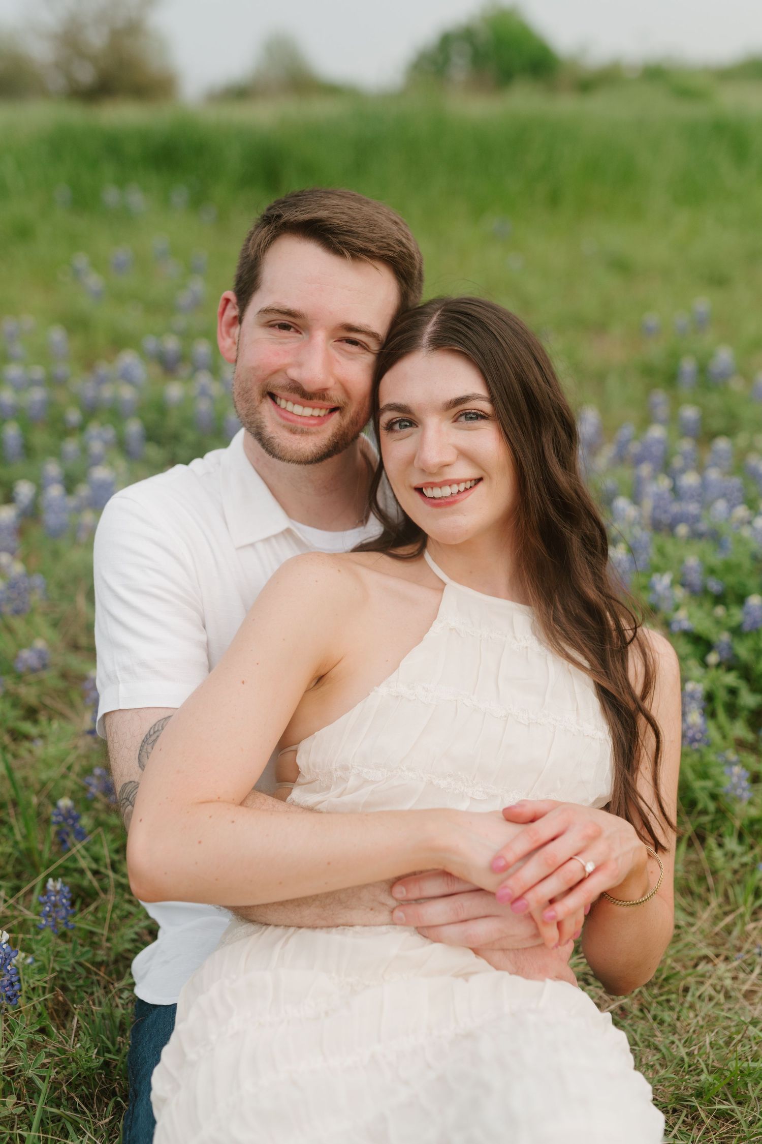 Engaged couple embracing in a field of bluebonnets during spring engagement photo session.