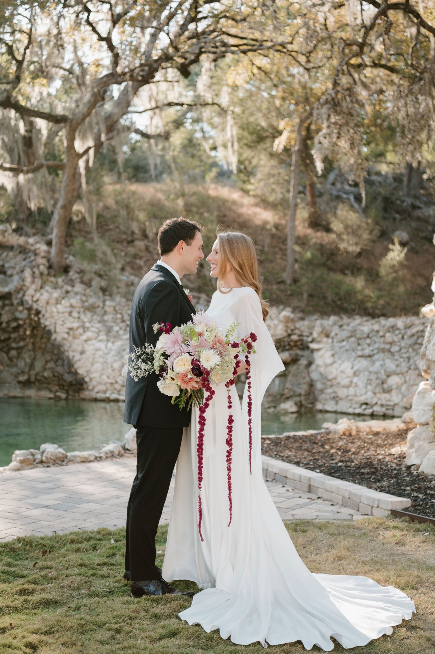 A romantic outdoor wedding scene with a couple by a scenic waterfront setting.