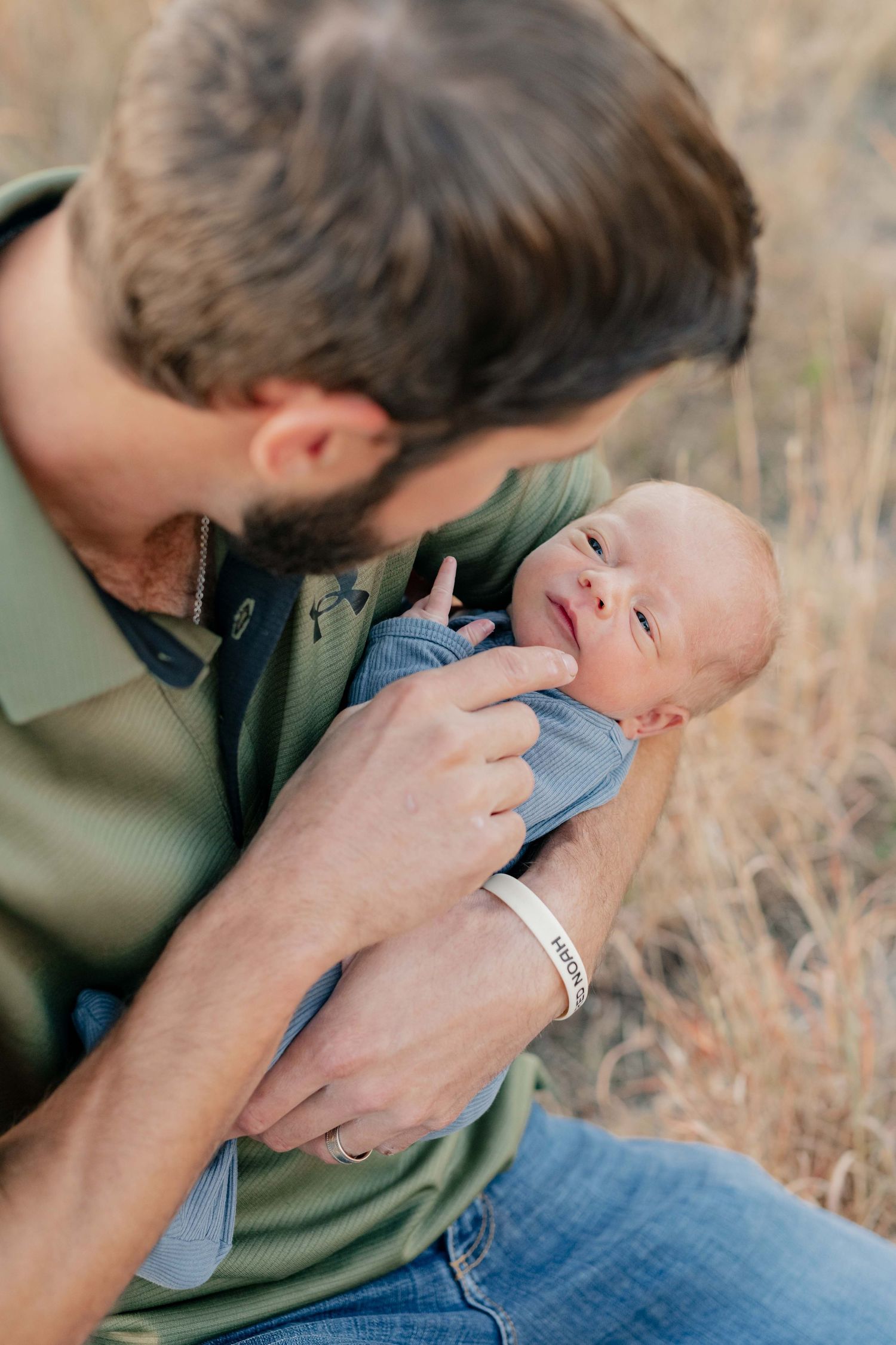 Close-up shot of a newborn baby being held while dressed in light blue clothing.